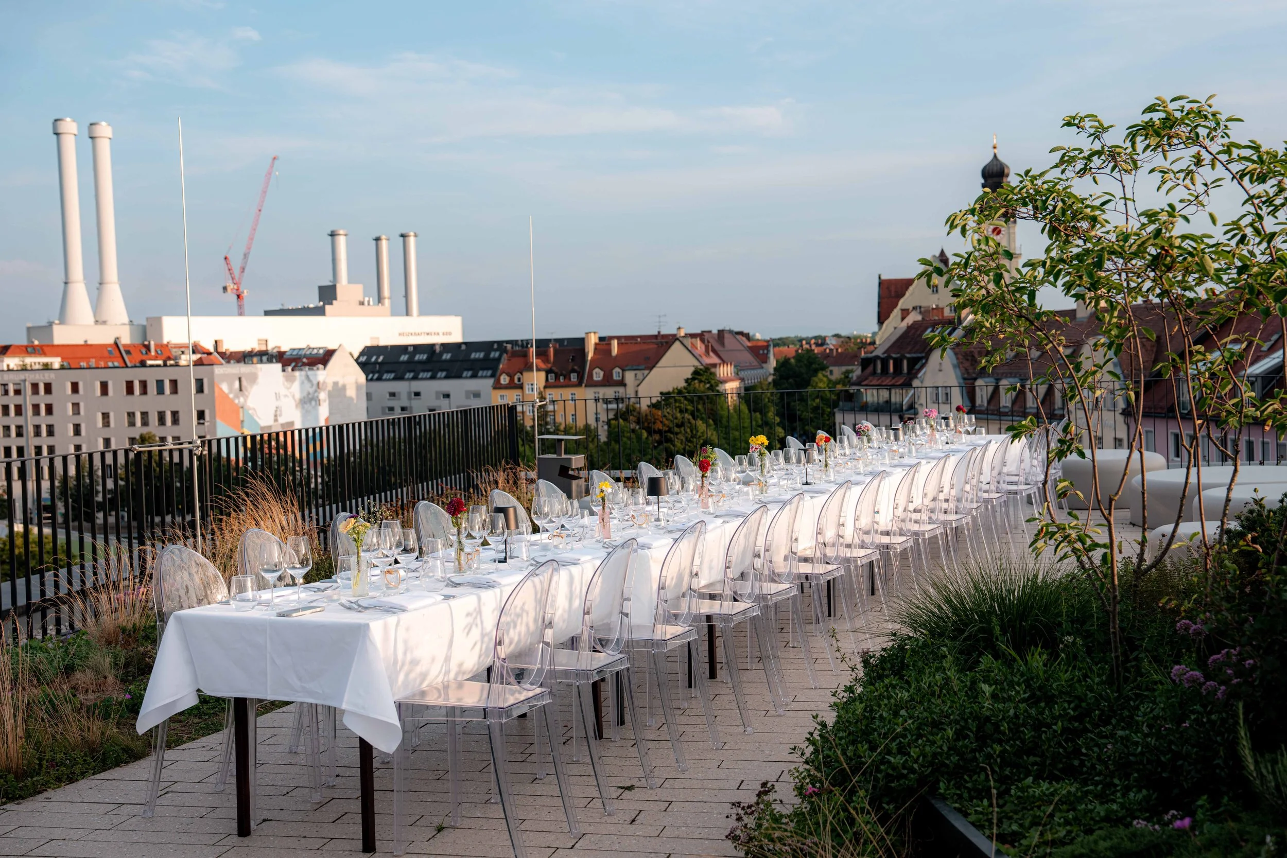 Exklusiv gedeckte Dinner-Tafel auf einer Rooftop-Location mit Blick über München. Hochwertige Firmenfeier-Ausstattung und Bankettmöbel mieten für Corporate Events.