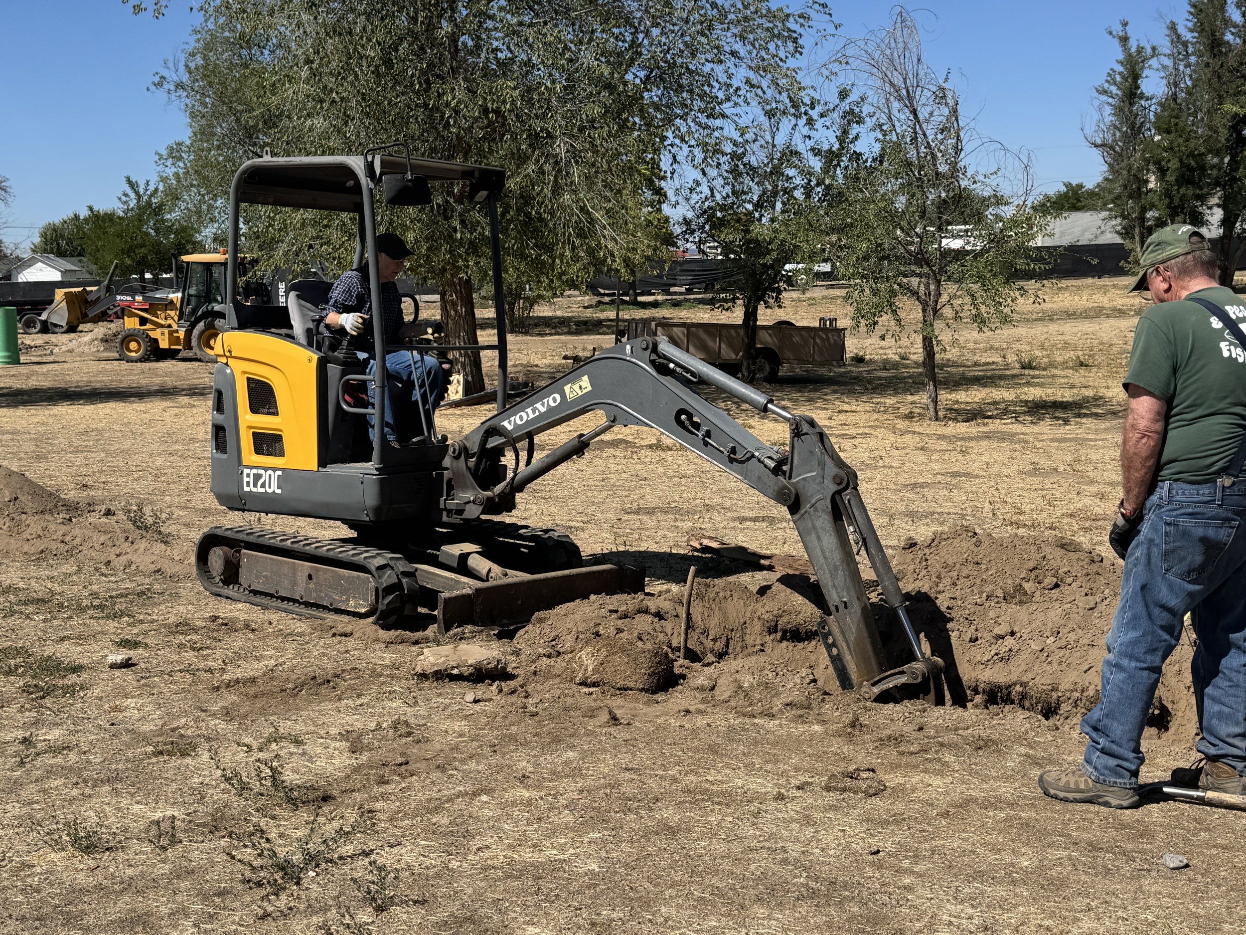 Marsha Schoeffler (Fiddle) and Bill Siems (Banjo) digging up some buried treasure while digging the trench for the power supply. Use of mini excavator donated by Rick Fereday. 