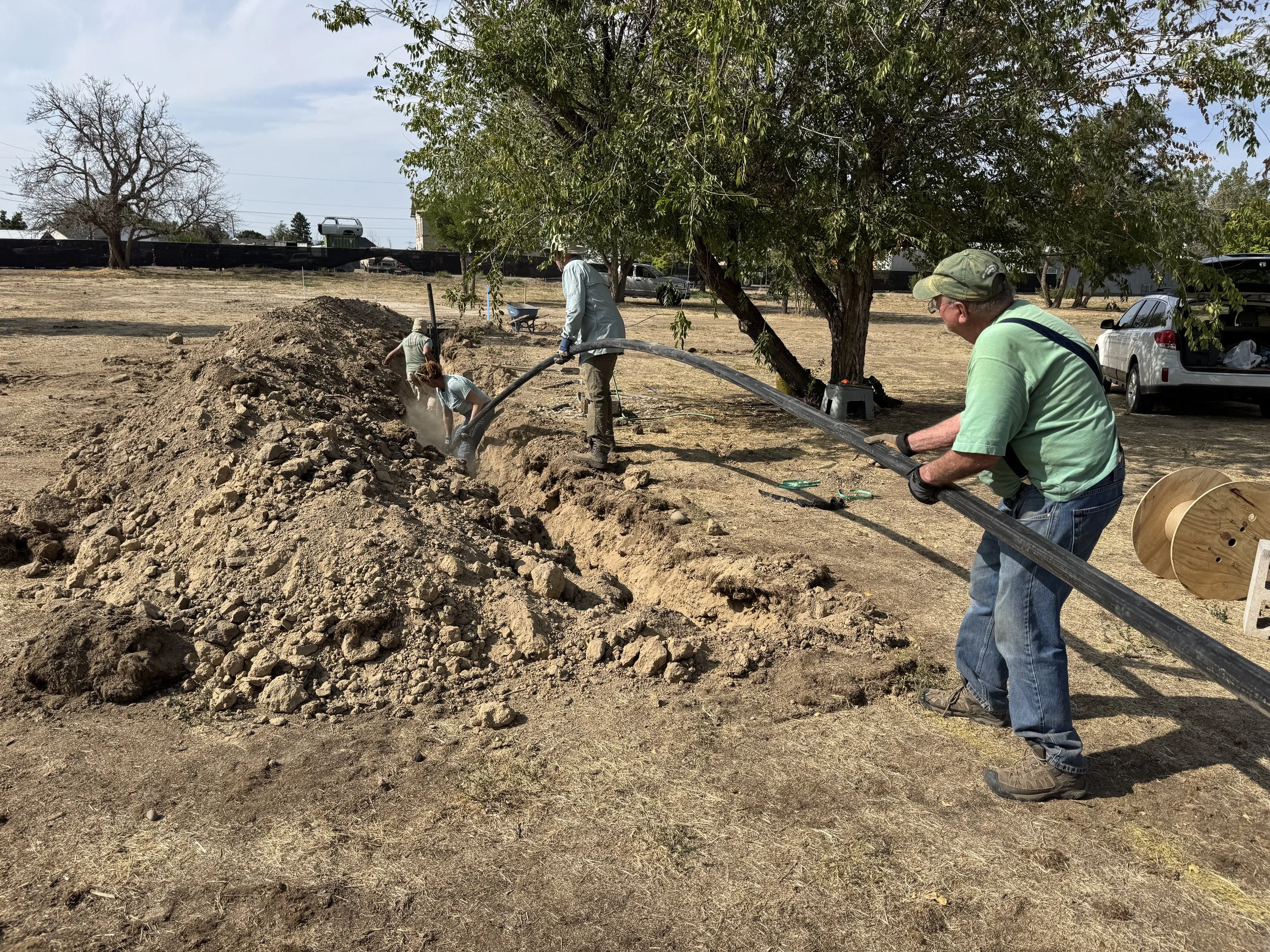Jeff Fereday (Guitar), Kate Little (Fiddle), Keith Walklet (Banjo) & Bill Siems (Mandolin) work to install the water supply line.