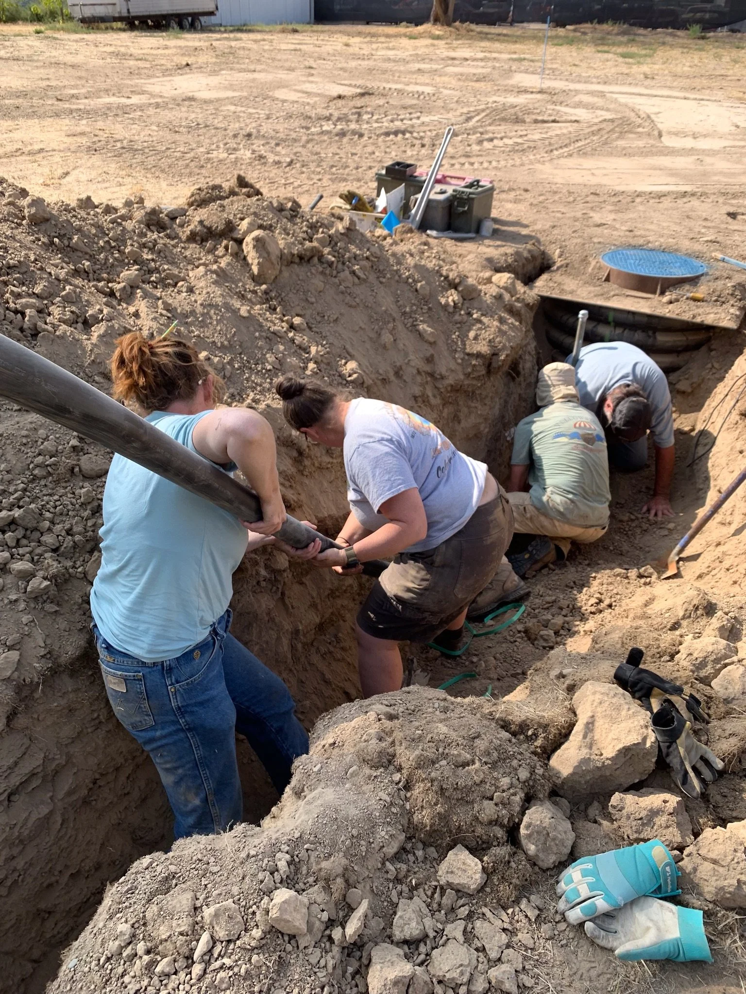 Volunteers Kate Little (Fiddle), Zondra Skertich (Bass), Jeff Fereday (Guitar) and Plumber Mike Conner (Guitar) connect the water supply line to city water.

