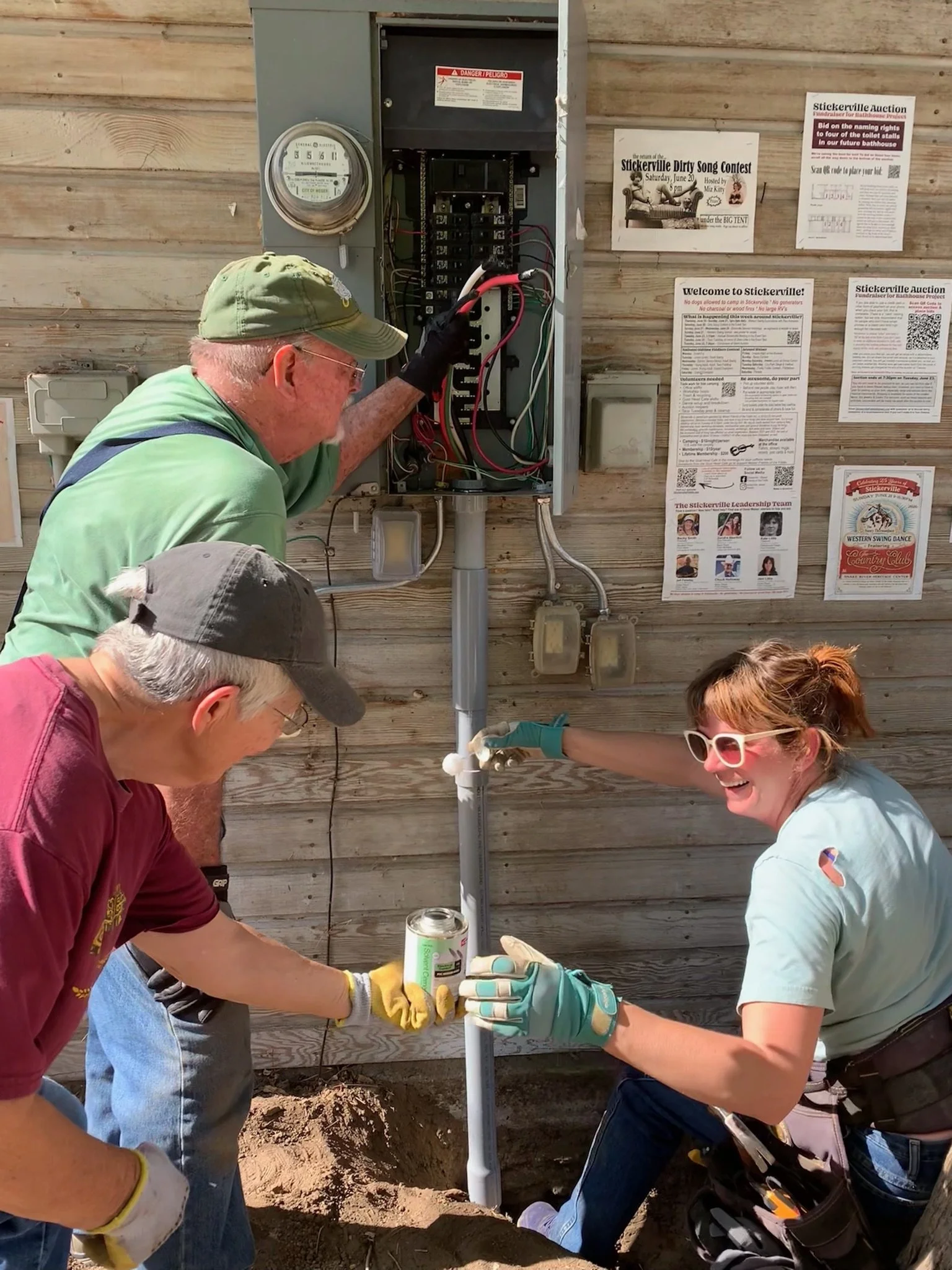 Marsha Schoeffler (Fiddle), Bill Siems (Mandolin) & Kate Little (Guitar) hooking up electrical and gluing conduit. 