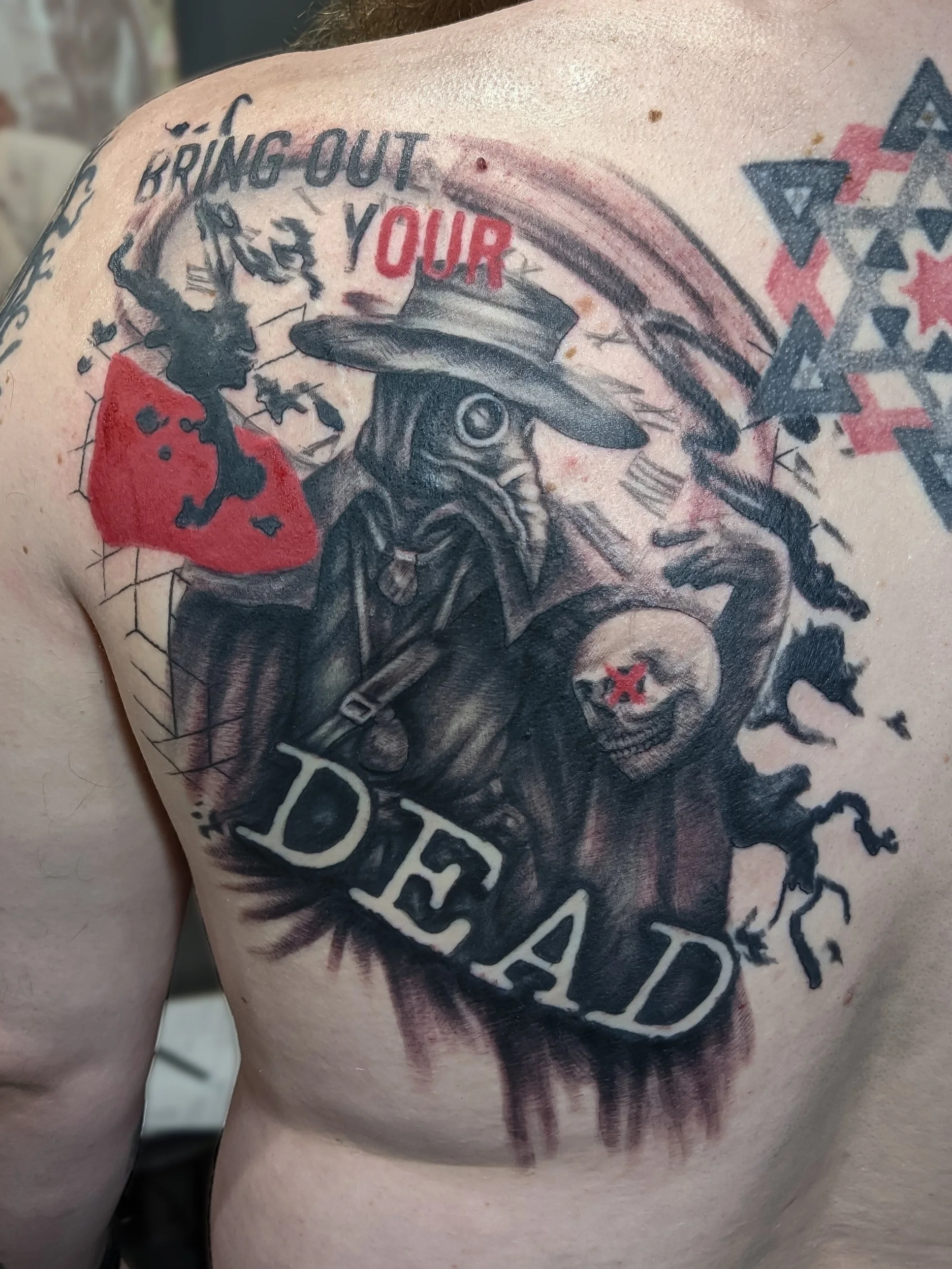 Tattoo on shoulder featuring a woman with a hat, scorpion, and a skull with a star inside. The tattoo includes text that reads 'BRING OUT YOUR.'