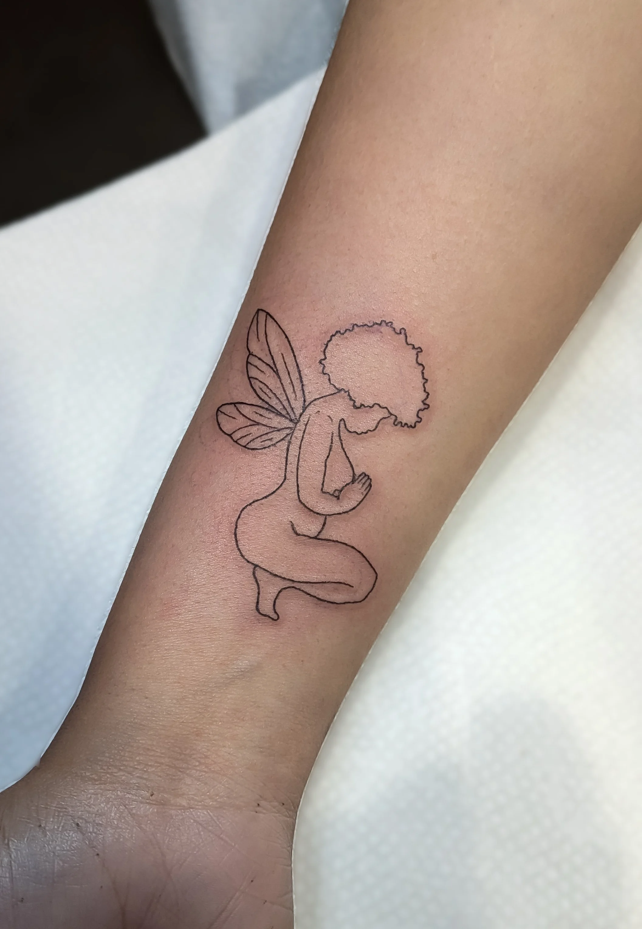 A tattoo of a fairy with butterfly wings on a person's arm.