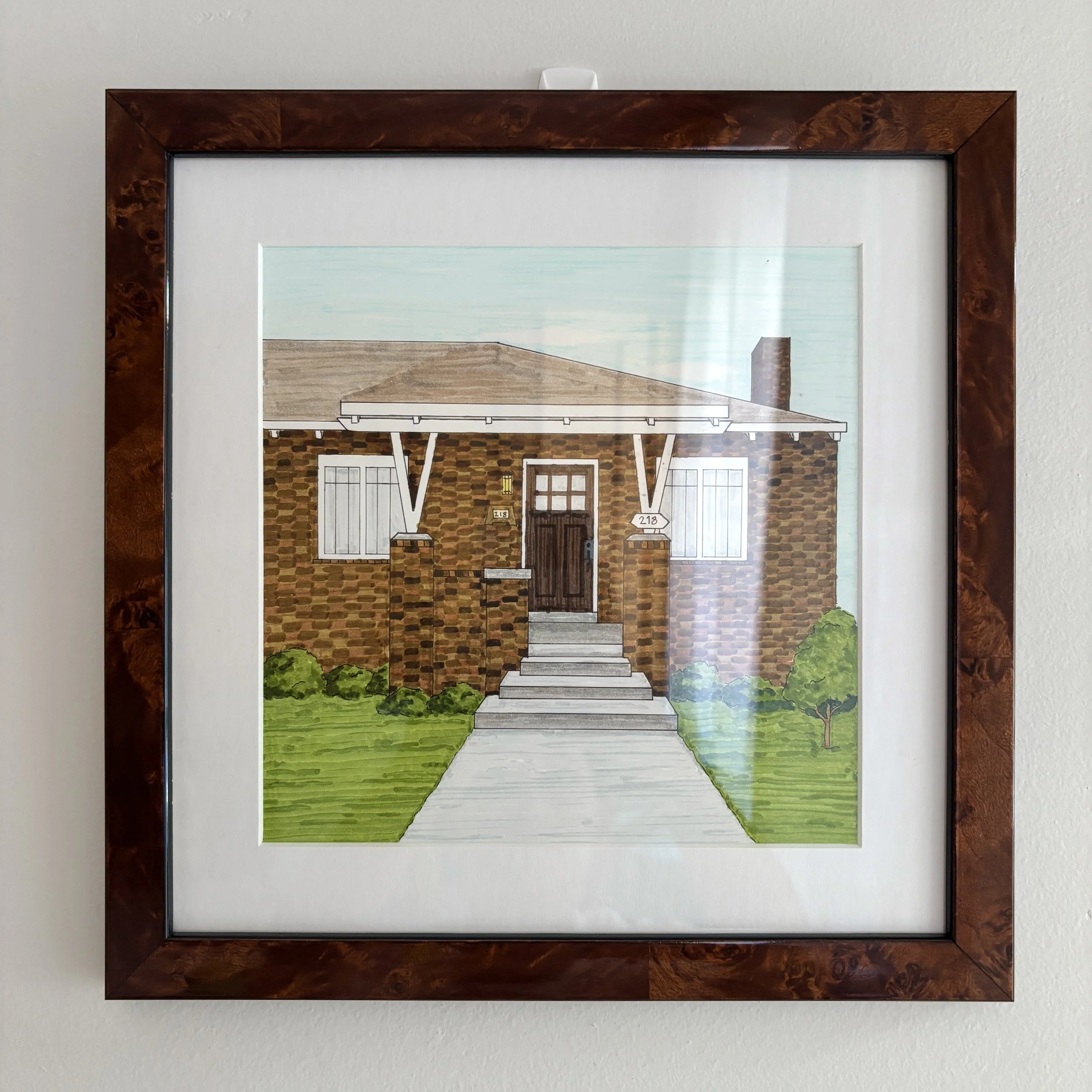 Drawing of a home framed in a dark wood frame.