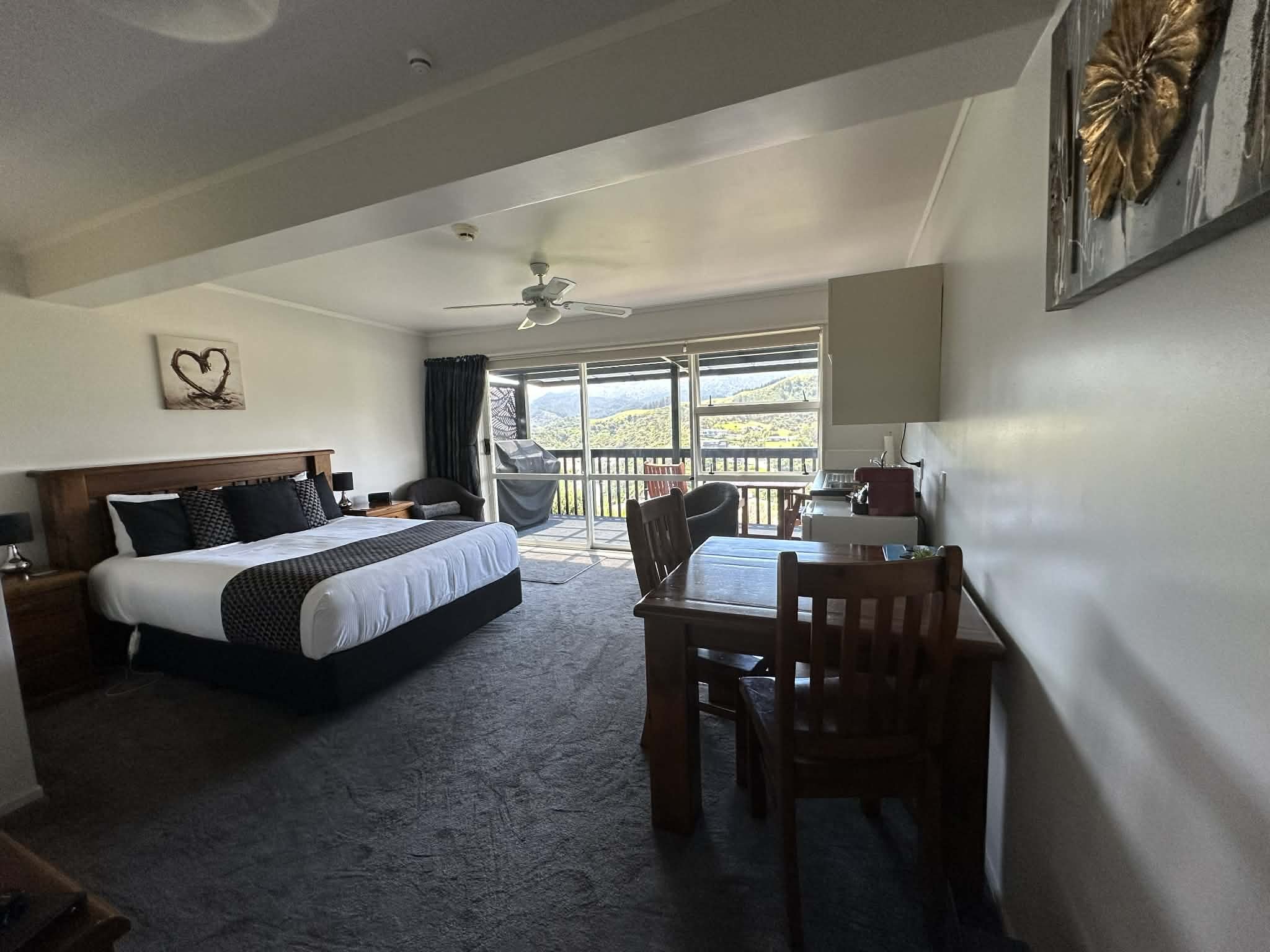 Deluxe Studio seating area with comfortable chairs and a peaceful view to the hills. Offering a peaceful spot to relax and enjoy Coromandel’s stunning scenery.