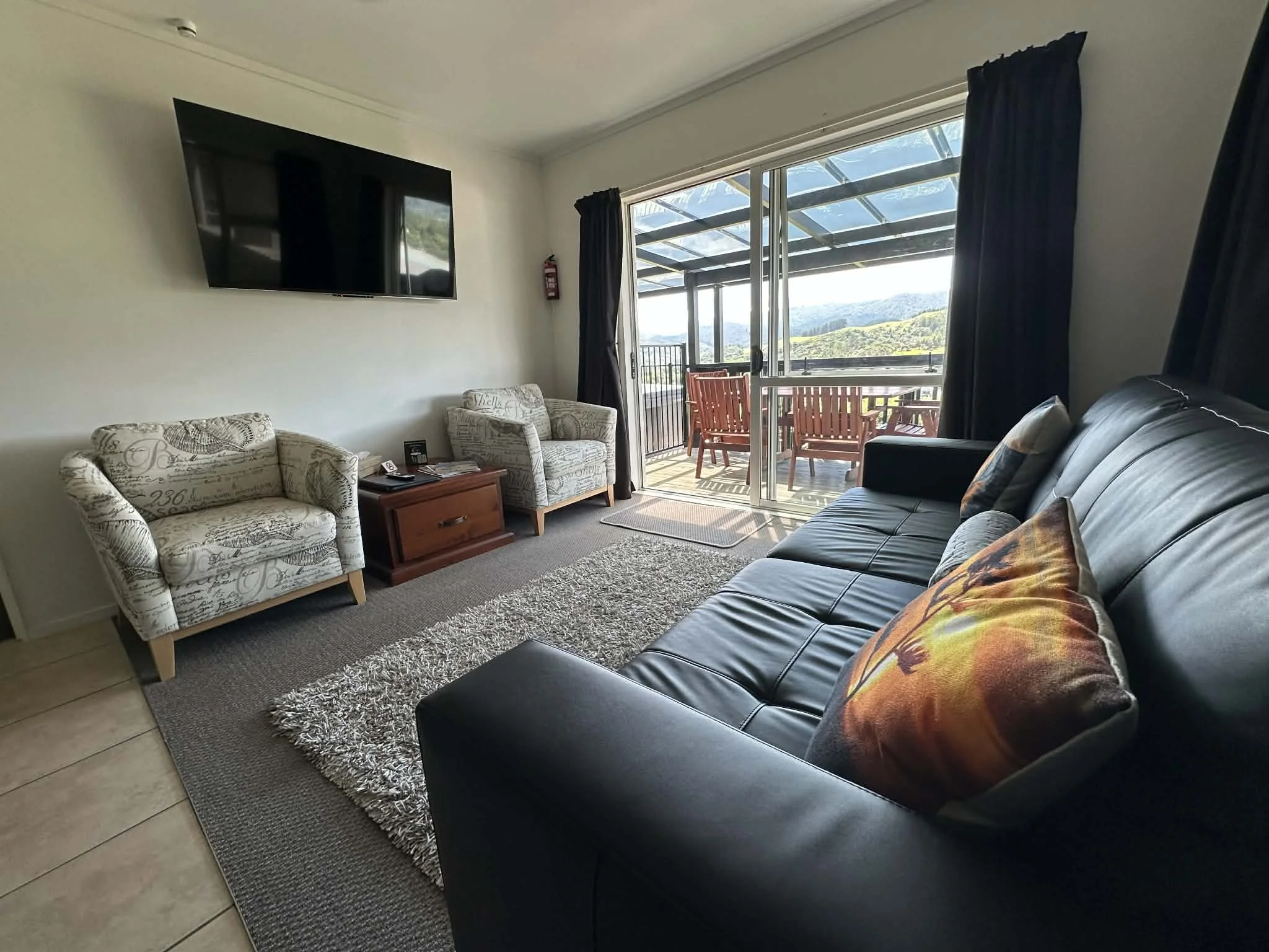 Comfortable Spa Apartment lounge with cosy seating and a relaxing view over the hills. Offering a peaceful spot to relax and enjoy Coromandel’s stunning scenery.