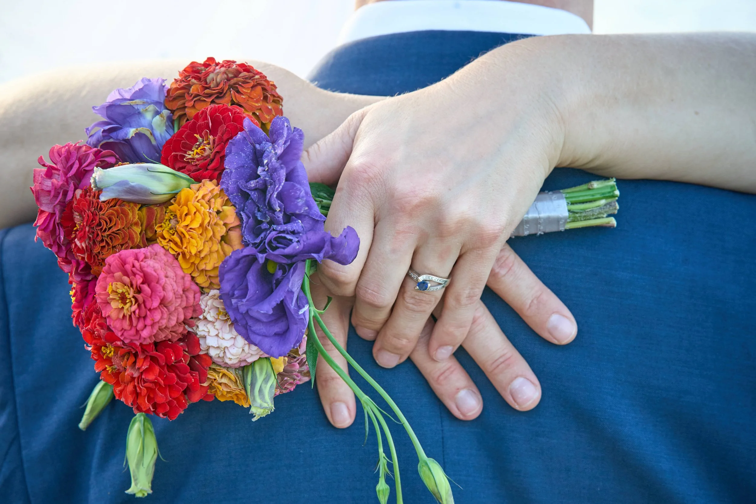 bride wraps her arms around groom showing off bouquet and ring photograph by Life Times Photography
