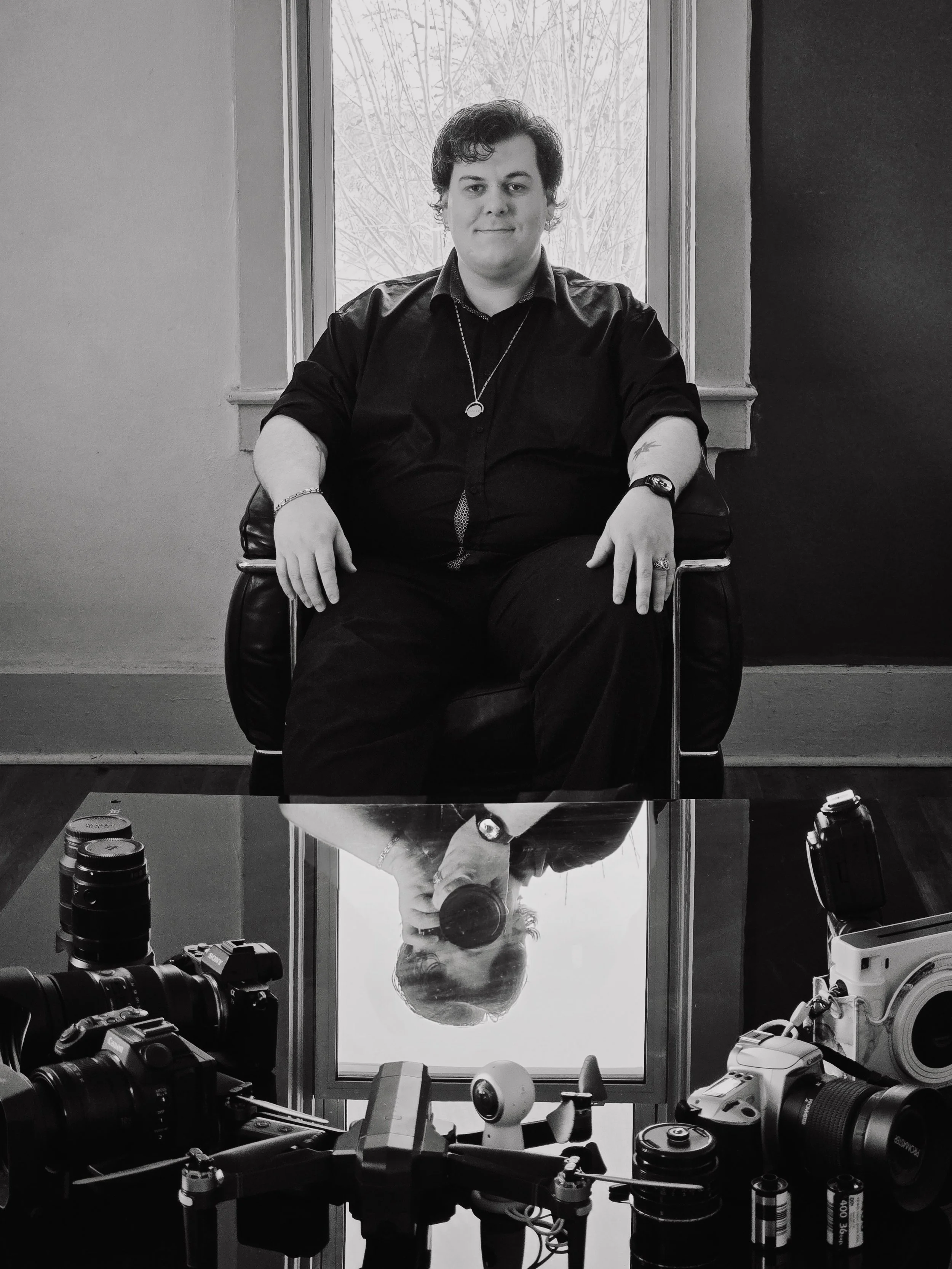 Person sitting in a chair with photography equipment on a reflective surface.