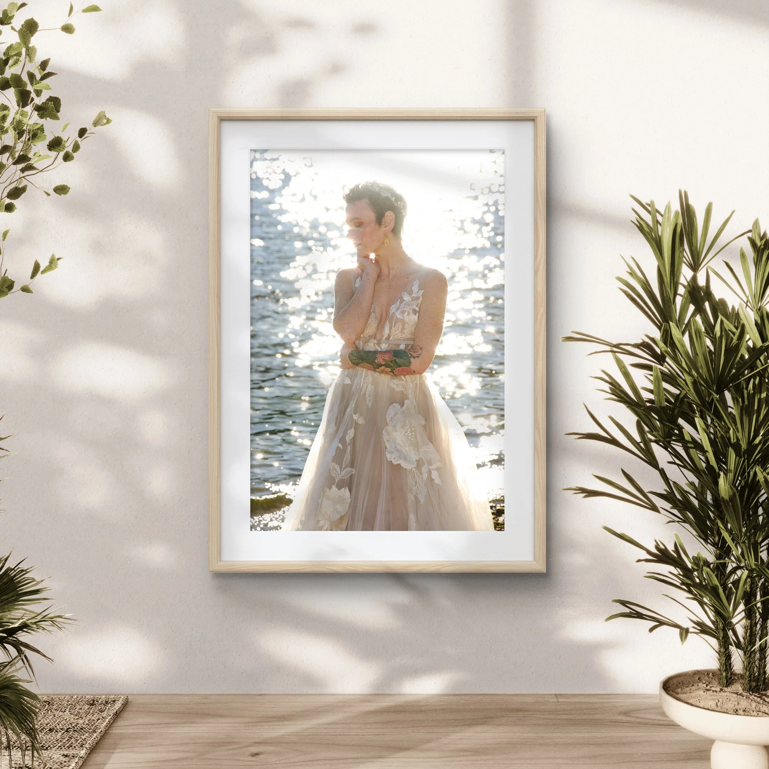 Framed photograph of a person in a floral dress by the water, surrounded by house plants.