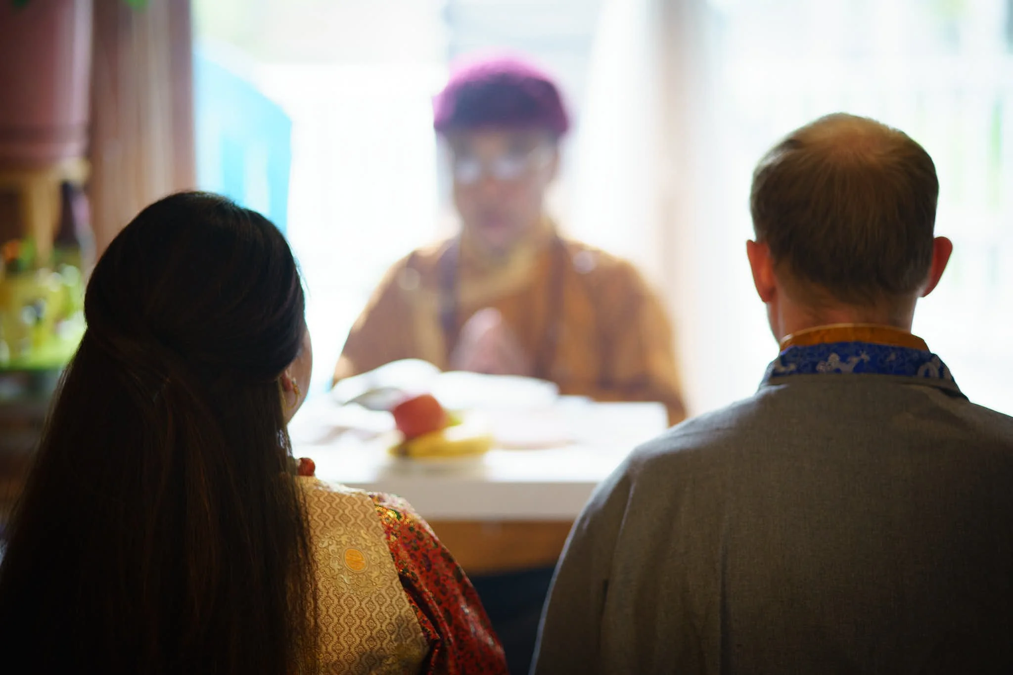 bride and groom sit before brides father during puja wedding ceremony photograph by Life Times Photography