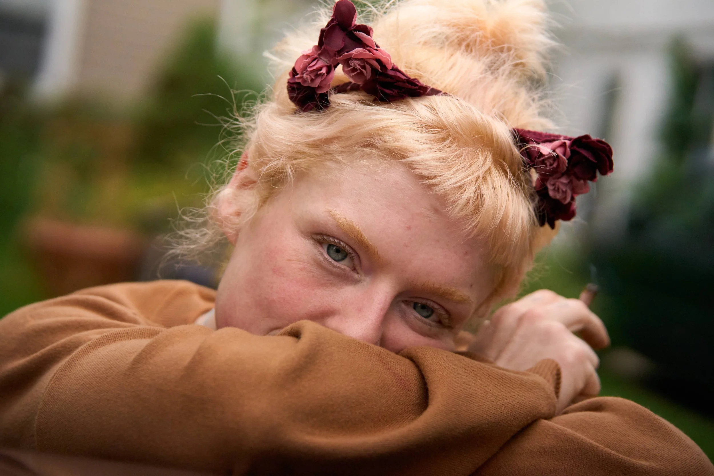 beautiful irish blonde in orange top hides bashful smile with beautiful green eyes holding hand rolled cigarette photograph by Life Times Photography