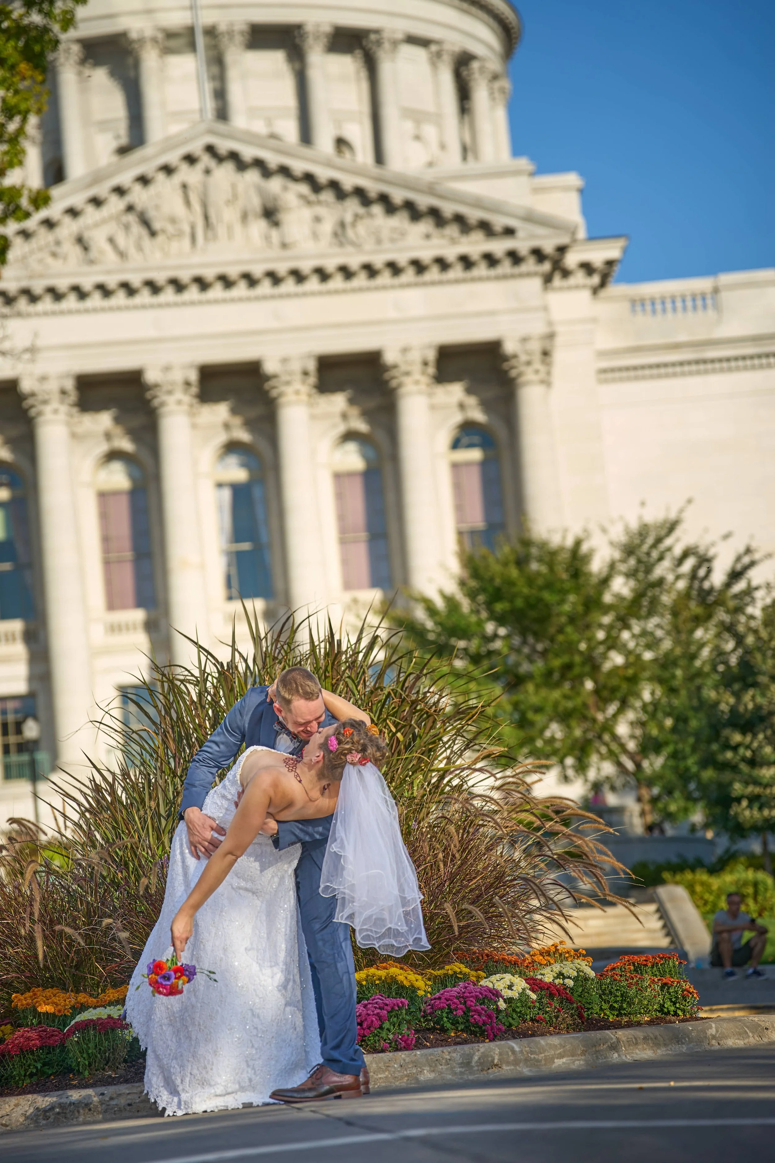 groom dips bride and kisses her in front of Wisconsin State Capitol photograph by Life Times Photography