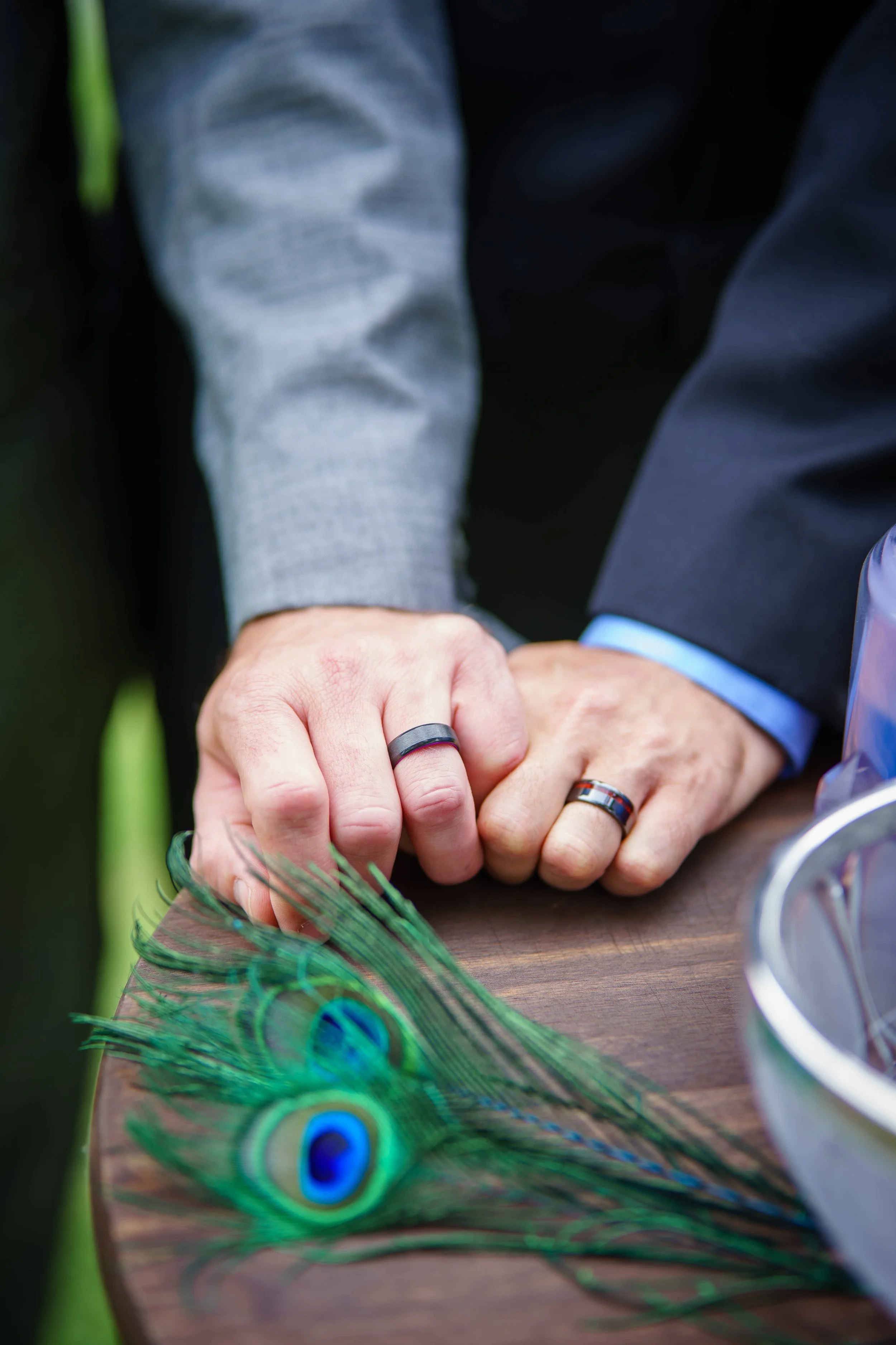 same sex couple show of their wedding rings resting their hands on wooden table photograph by Life Times Photography