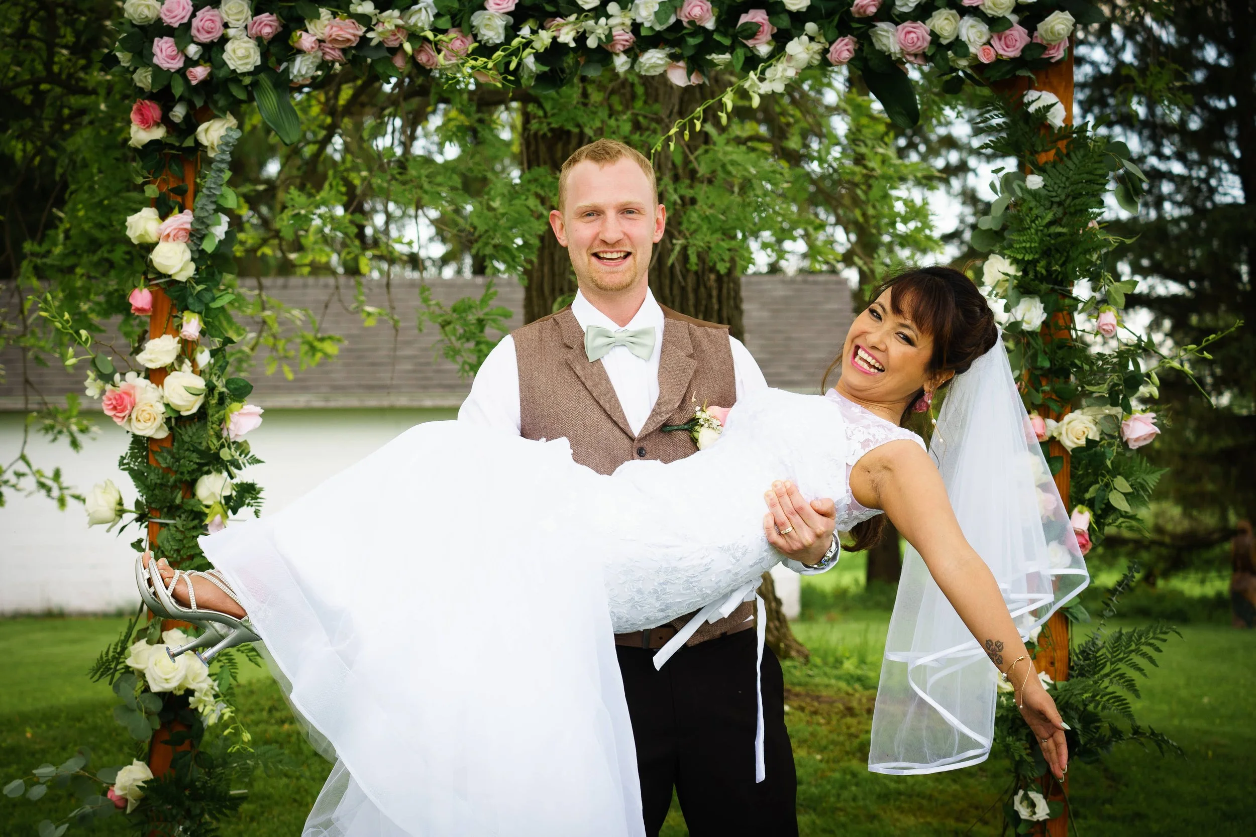 groom holds bride in arms after wedding ceremony photograph by Life Times Photography
