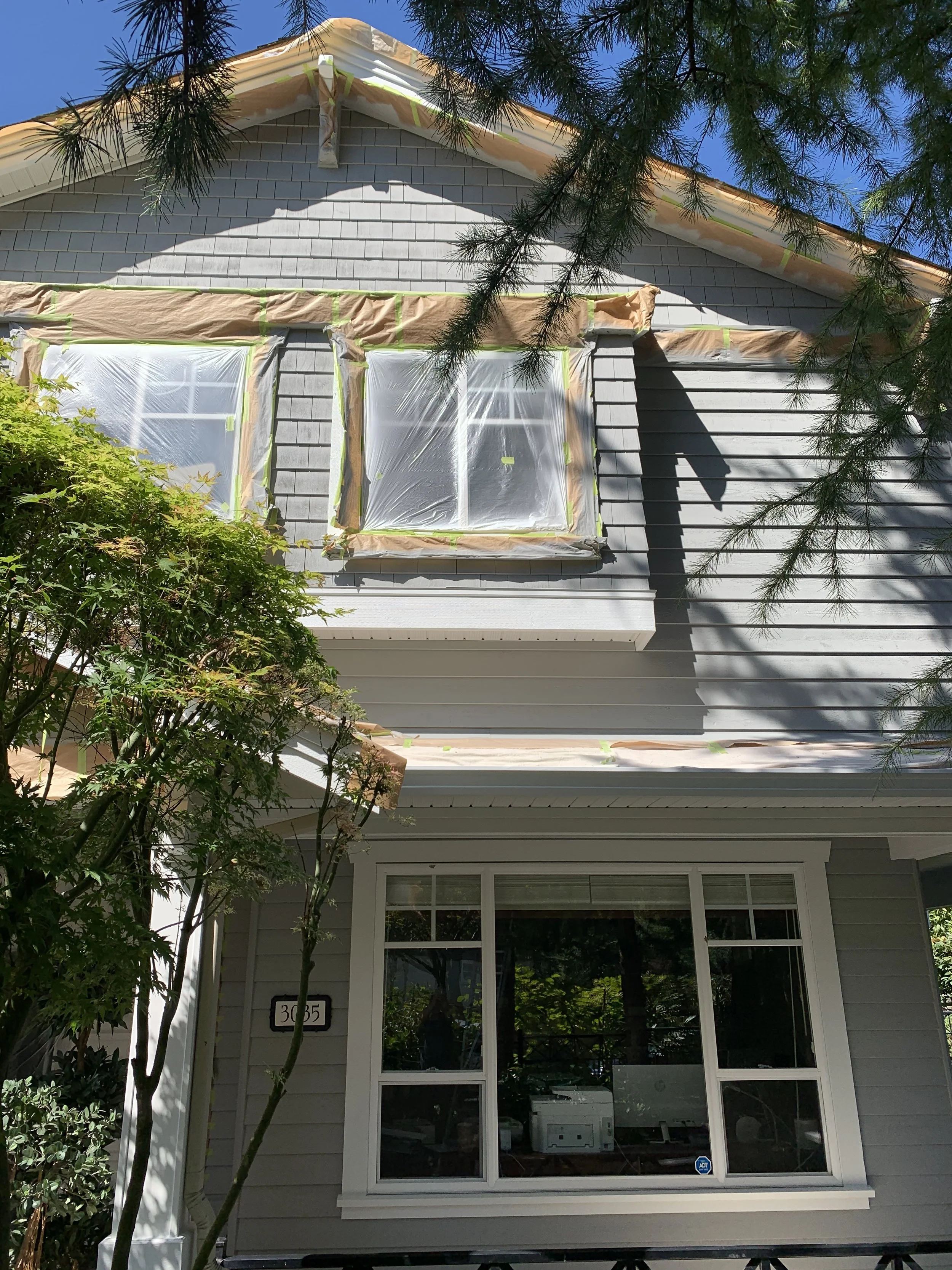 exterior painting, exterior of the house prepped for spraying, masked off windows, North Vancouver painting company