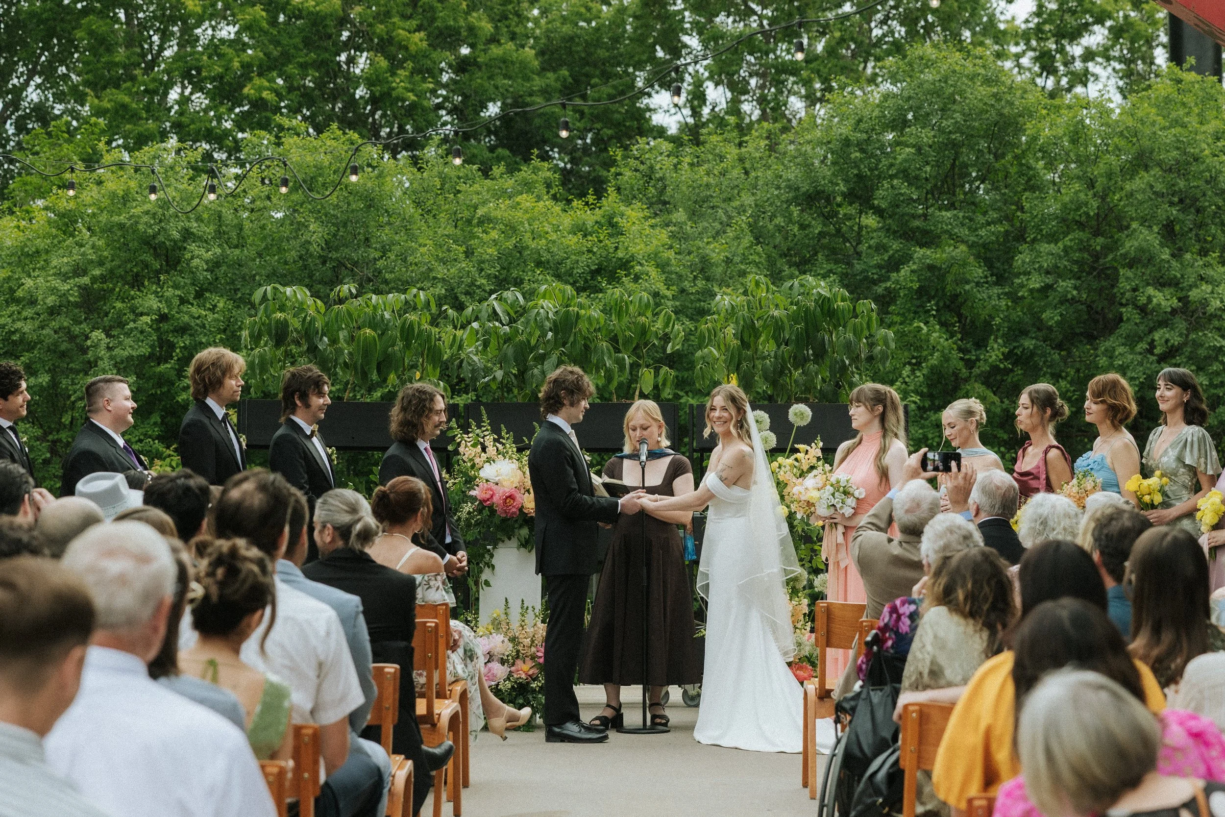 An outdoor wedding ceremony in the café-lit courtyard at PAIKKA, a St. Paul wedding venue