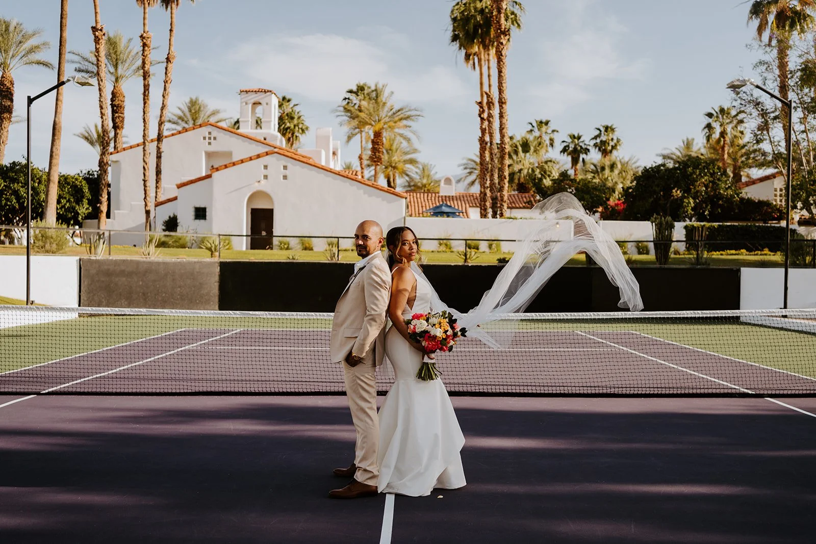 Bride and groom wedding portrait on the tennis court at La Quinta Resort with veil blowing in the wind Palm Springs wedding photographer Tida Svy