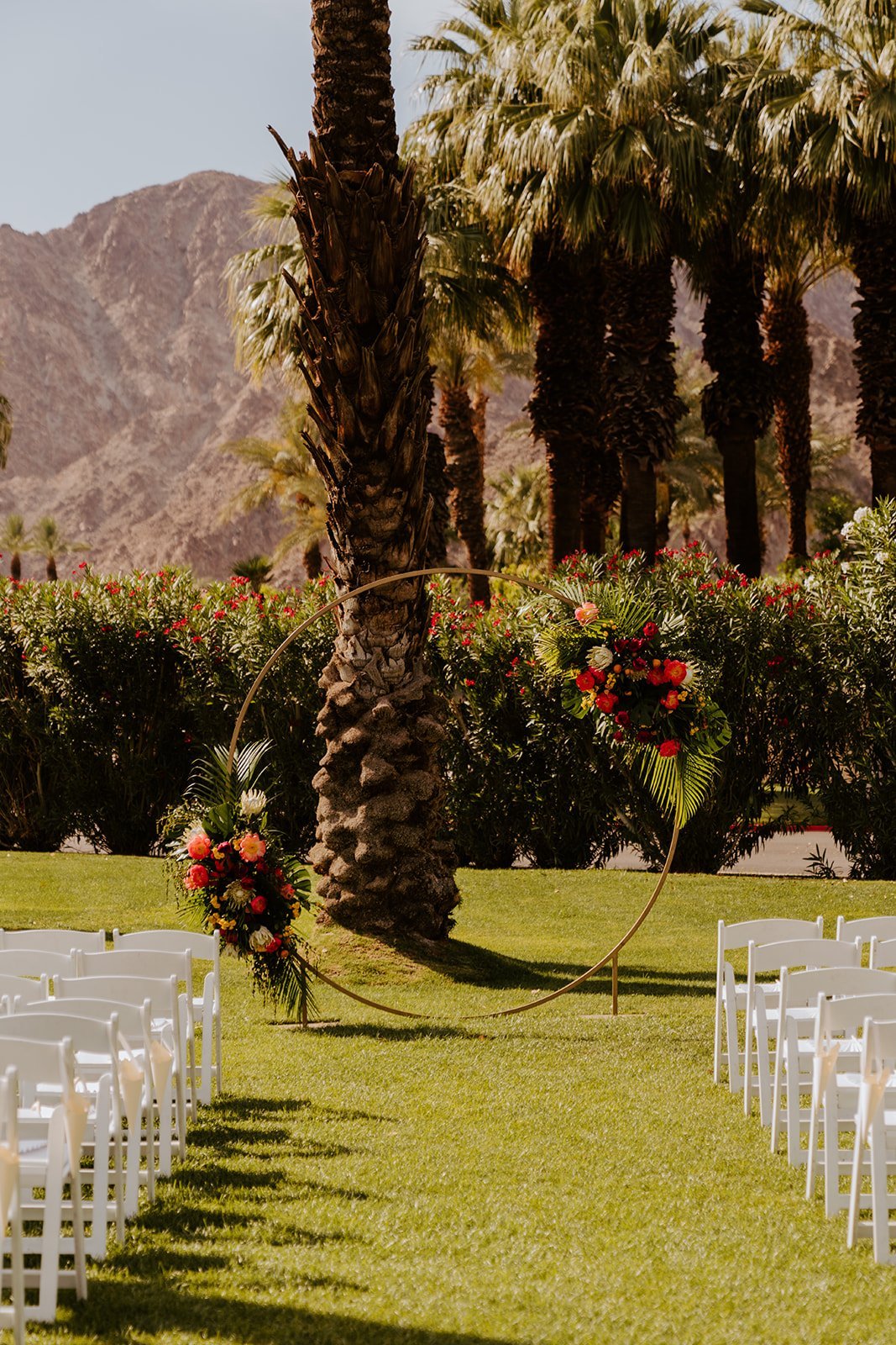 Colorful tropical floral ceremony arch, wedding at La Quinta Resort in Palm Springs | photo by Tida Svy