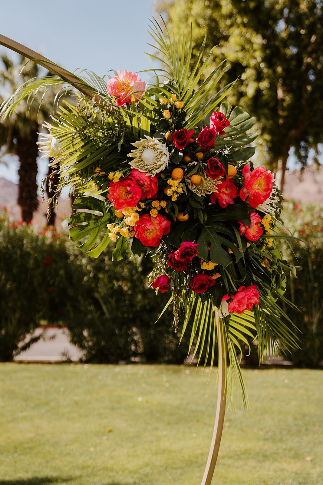 Colorful tropical floral ceremony arch, wedding at La Quinta Resort in Palm Springs | photo by Tida Svy