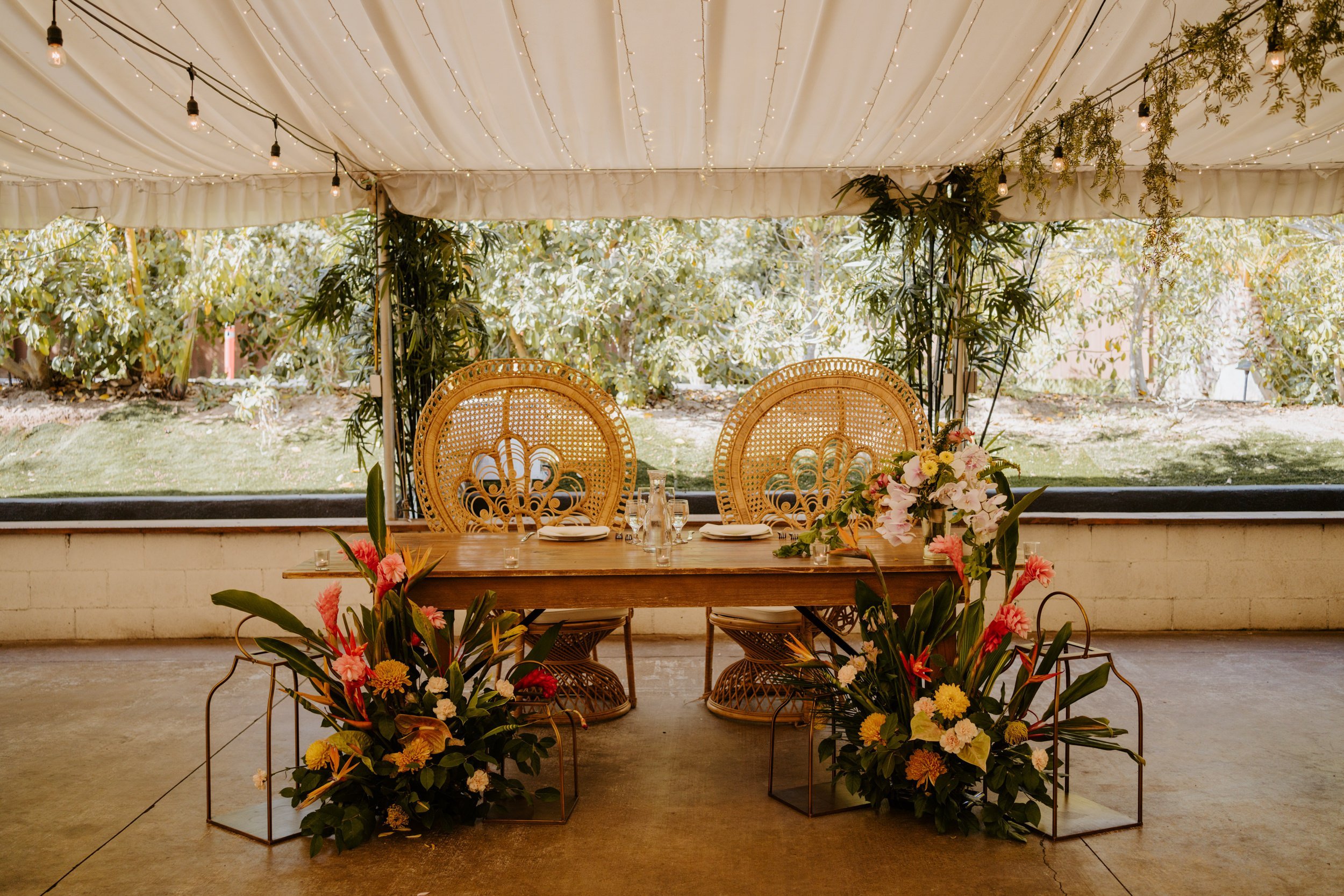 Tropical boho inspired wedding sweetheart table with peacock chairs. Botanica Oceanside wedding reception, San Diego wedding venue, photo by TIda Svy, San Diego wedding photographer