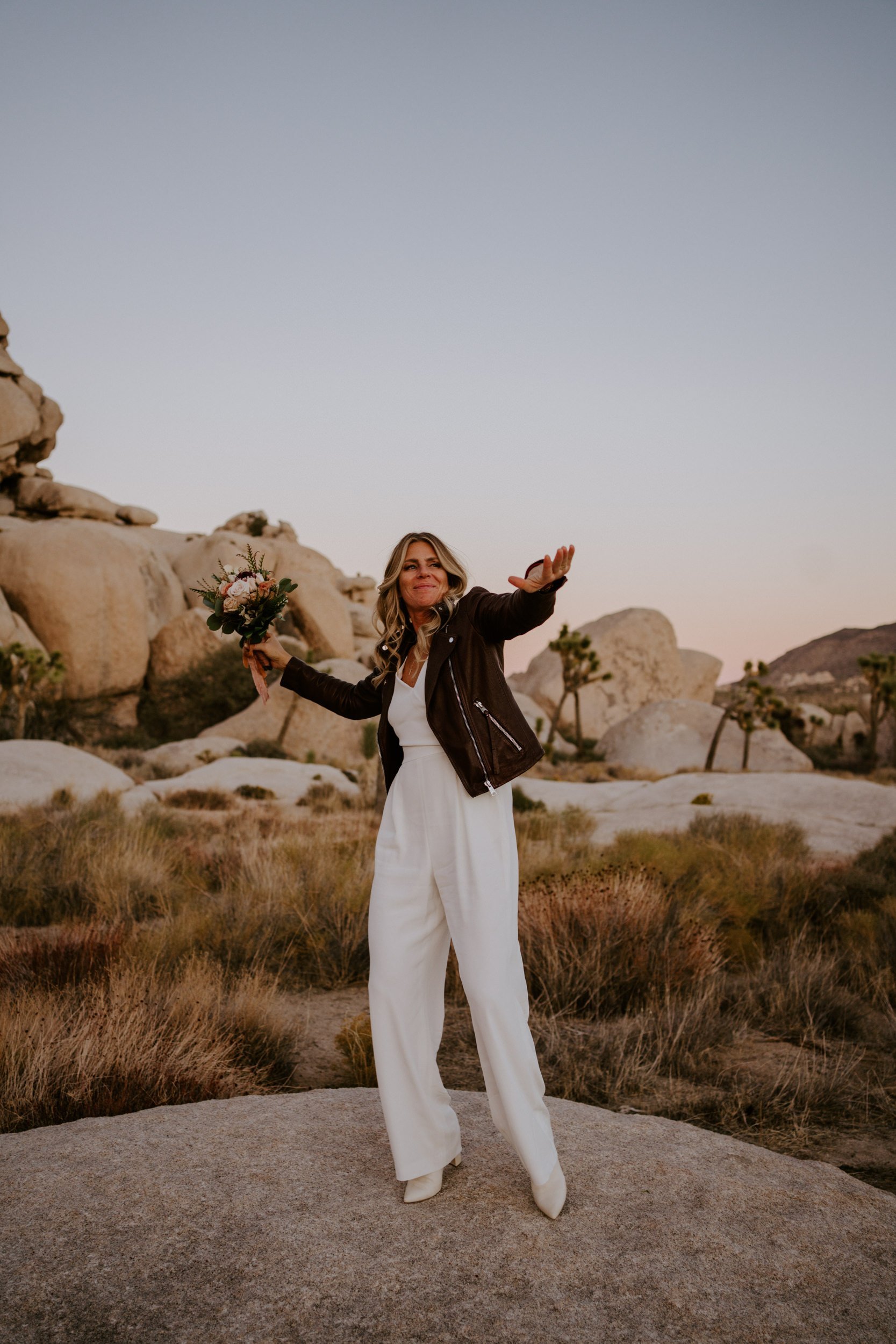 Rock N Roll bride in white jumpsuit and leather jacket, Joshua Tree bridal style, Photo by Tida Svy