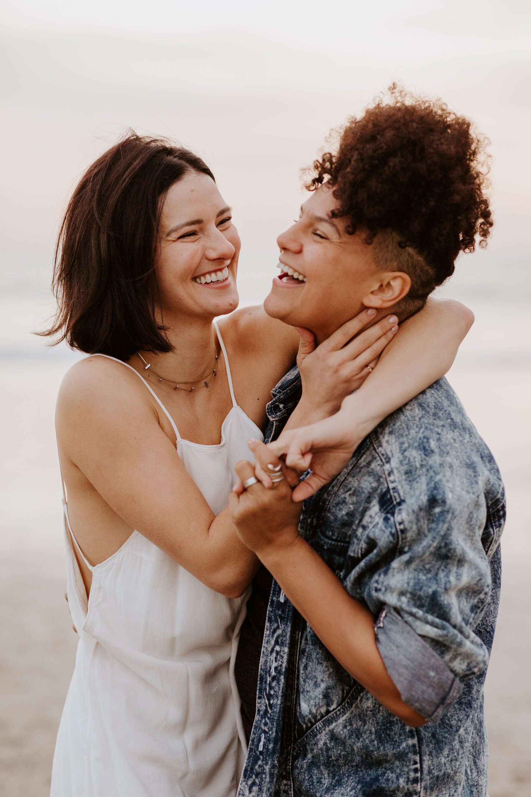 Lesbian couple laughing and holding hands during their Venice Beach engagement session, Photography by LGBTQ friendly wedding photographer Tida Svy