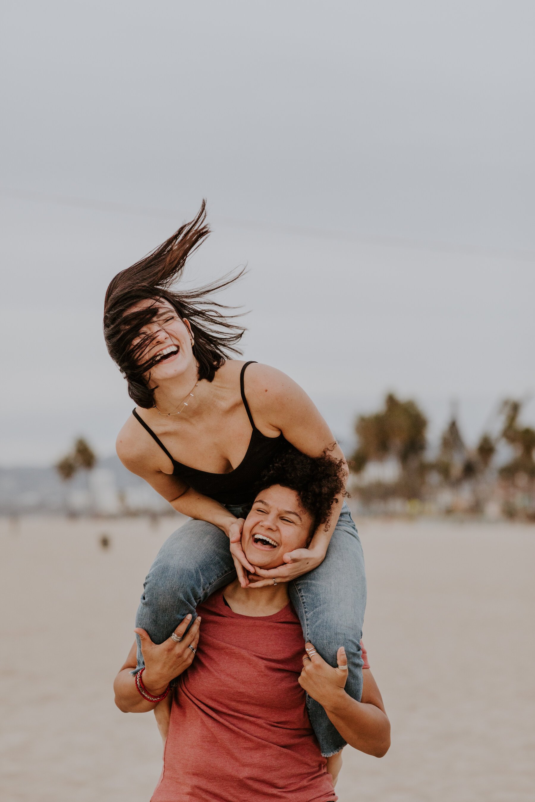 Playful and fun lesbian engagement session pose in Venice Beach, CA, Photography by Tida Svy