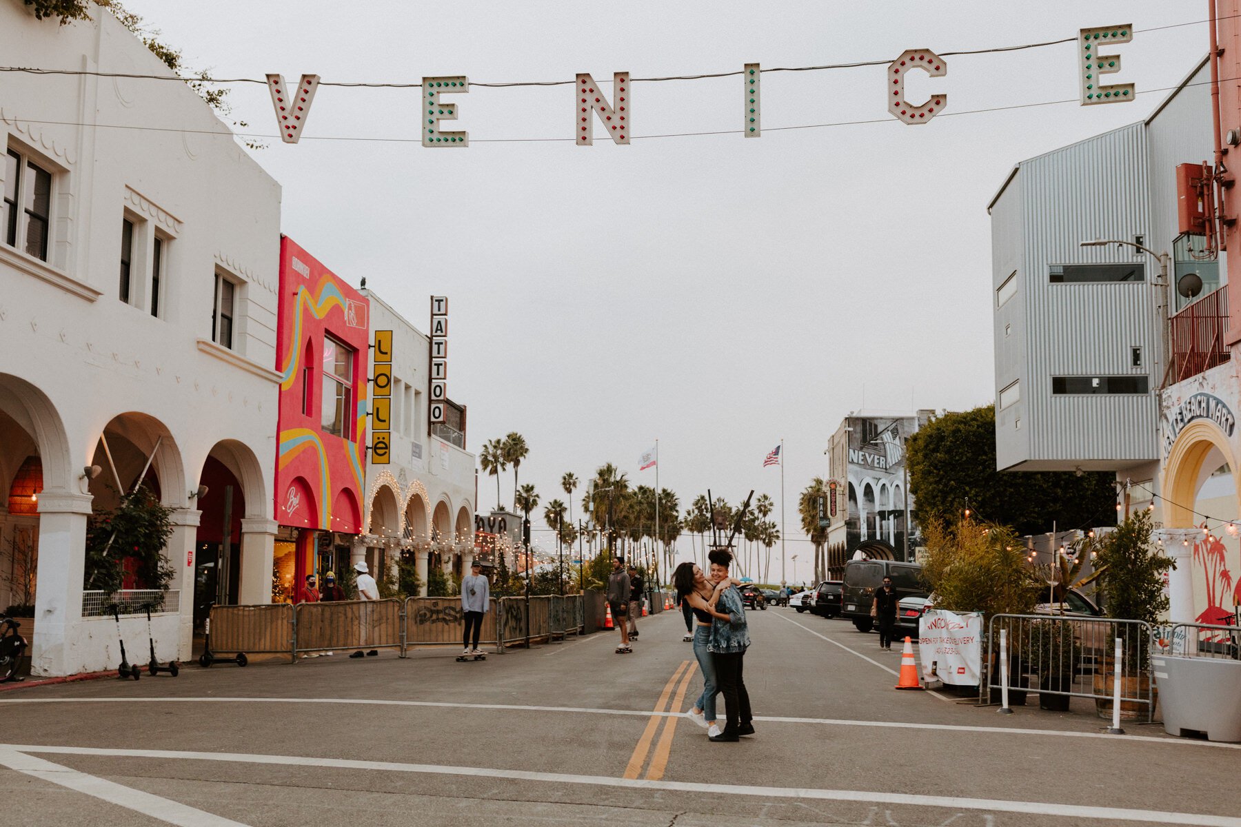 Lesbian couple under the Venice sign in Venice Beach for their engagement session, Photography by Tida Svy