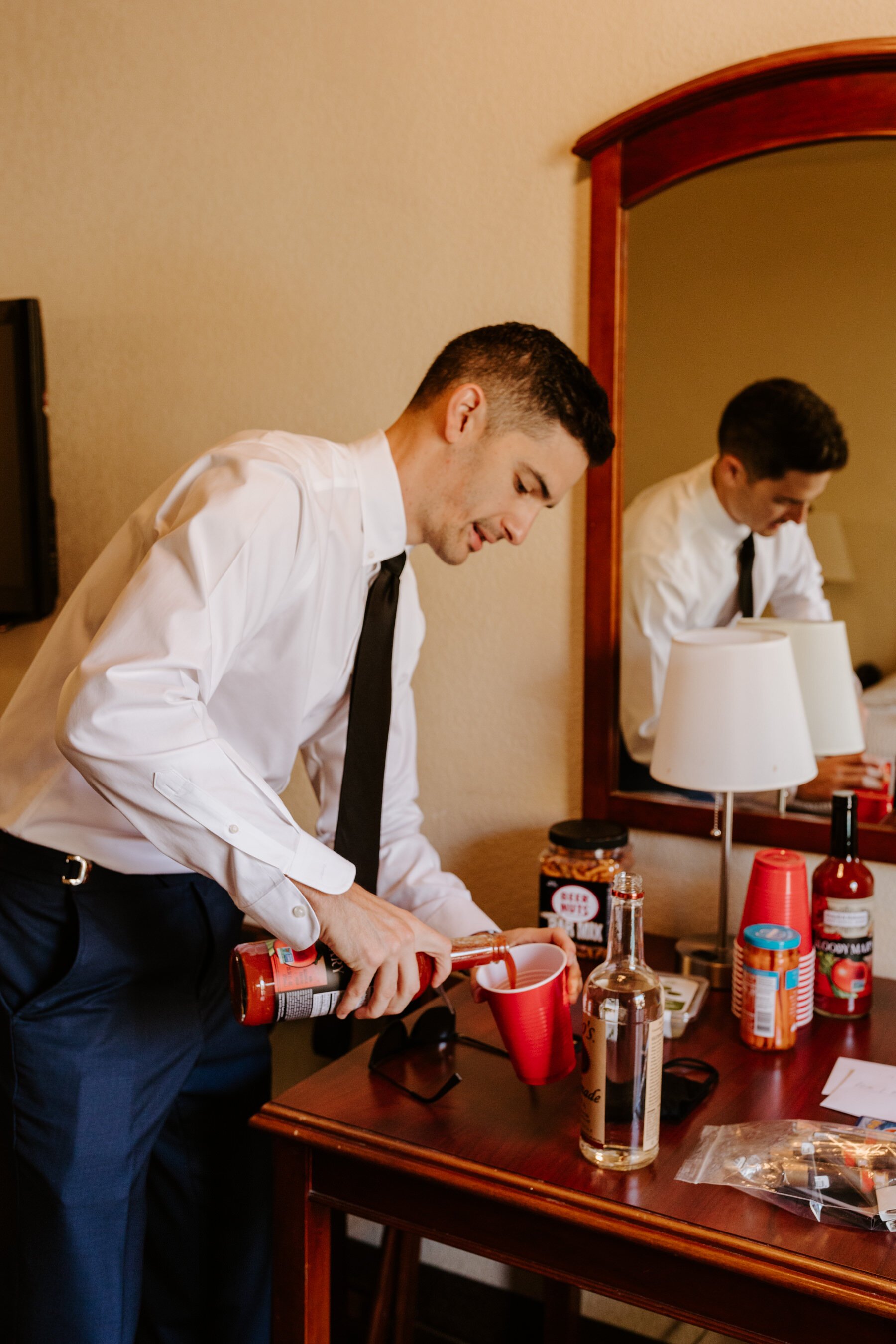 Best man pouring drink getting ready at Palm Mountain Resort Hotel, Palm Springs Wedding Photographer, Tida Svy Photography