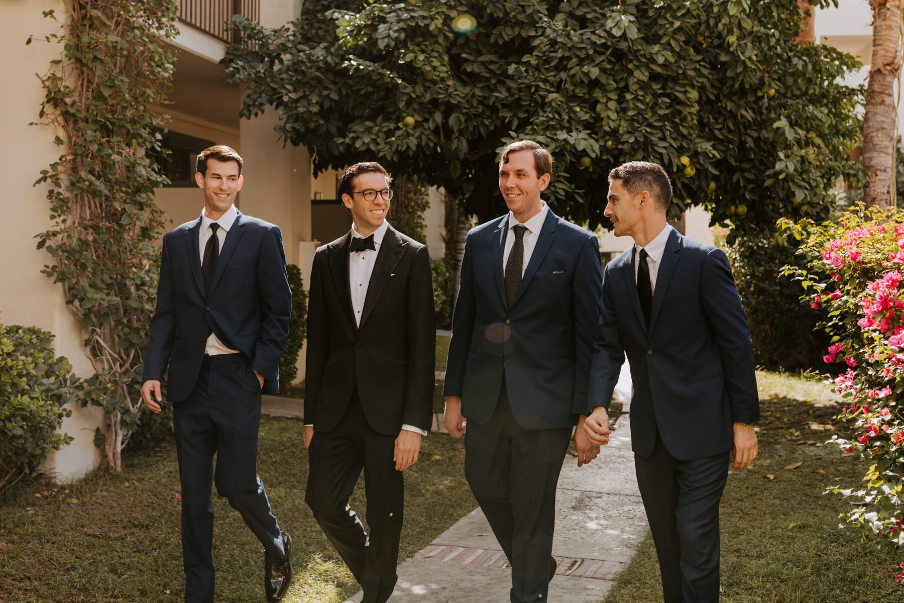 Groomsmen and Groom walking and looking at each other laughing at Palm Mountain Resort Hotel, Palm Springs Wedding Photographer, Tida Svy Photography