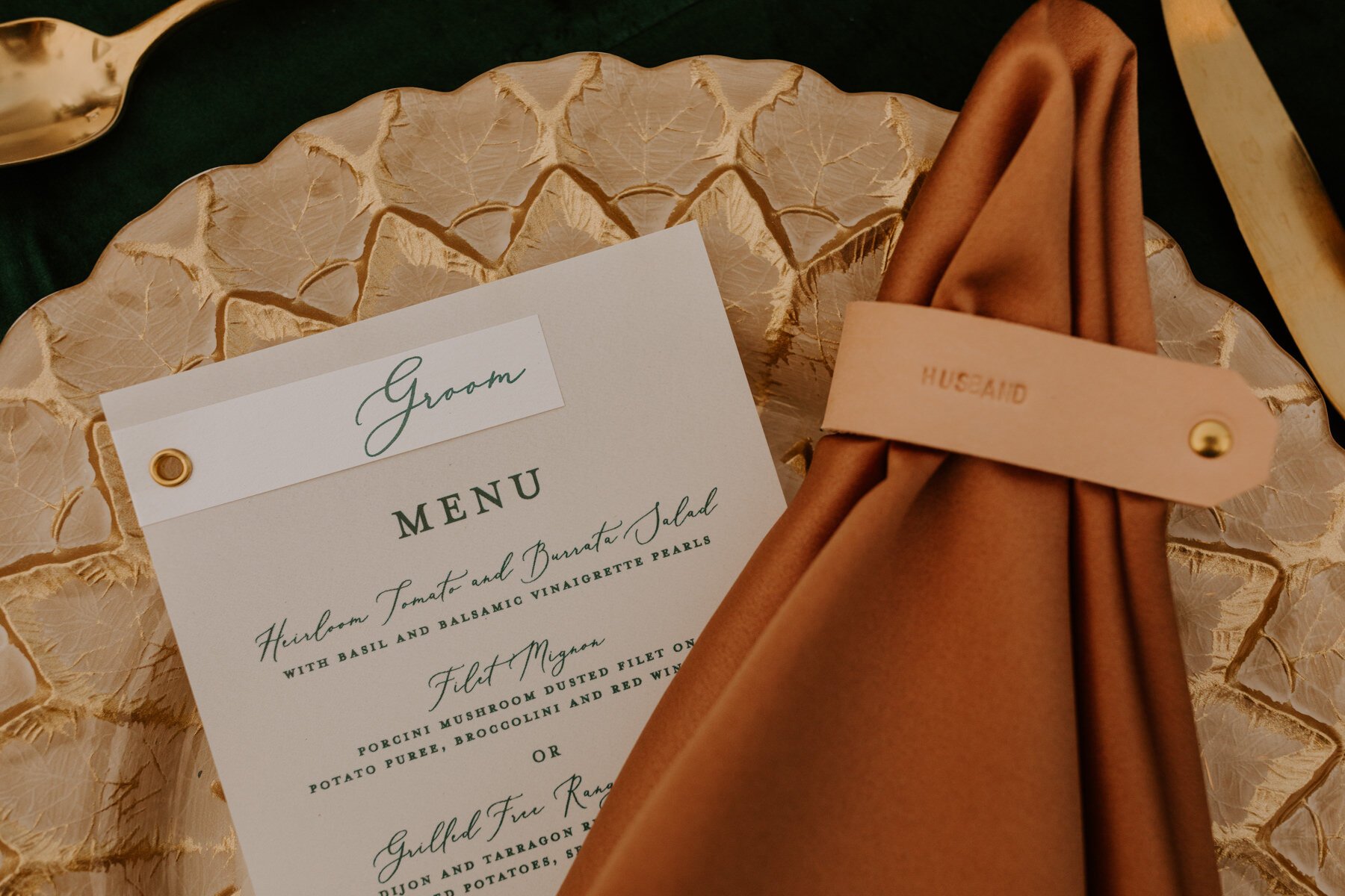 Gold charger, beige napkin, leather napkin ring, modern jewel toned inspired wedding place setting.