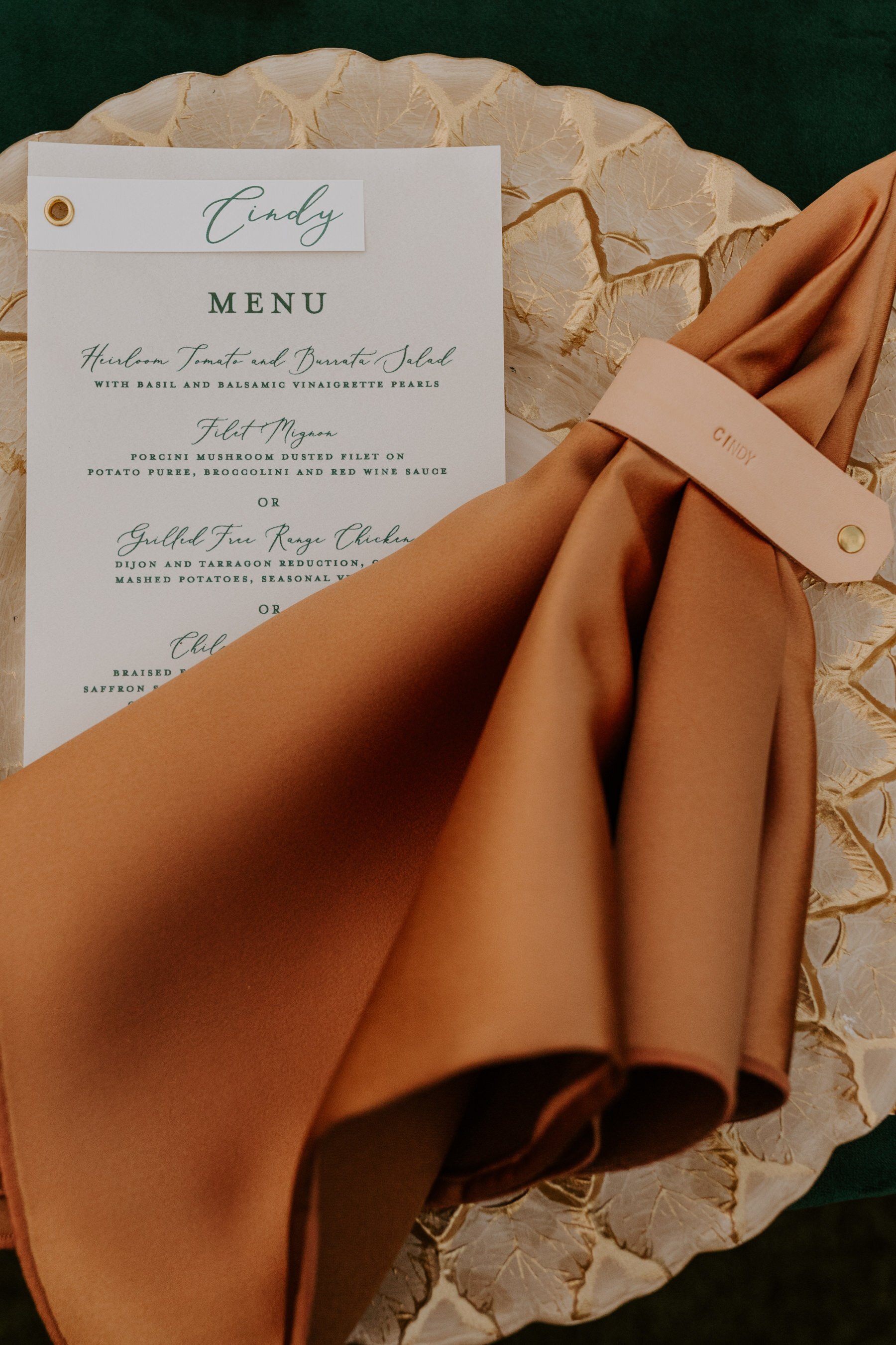 Gold charger, orange napkin, leather napkin ring, modern jewel toned inspired wedding place setting.