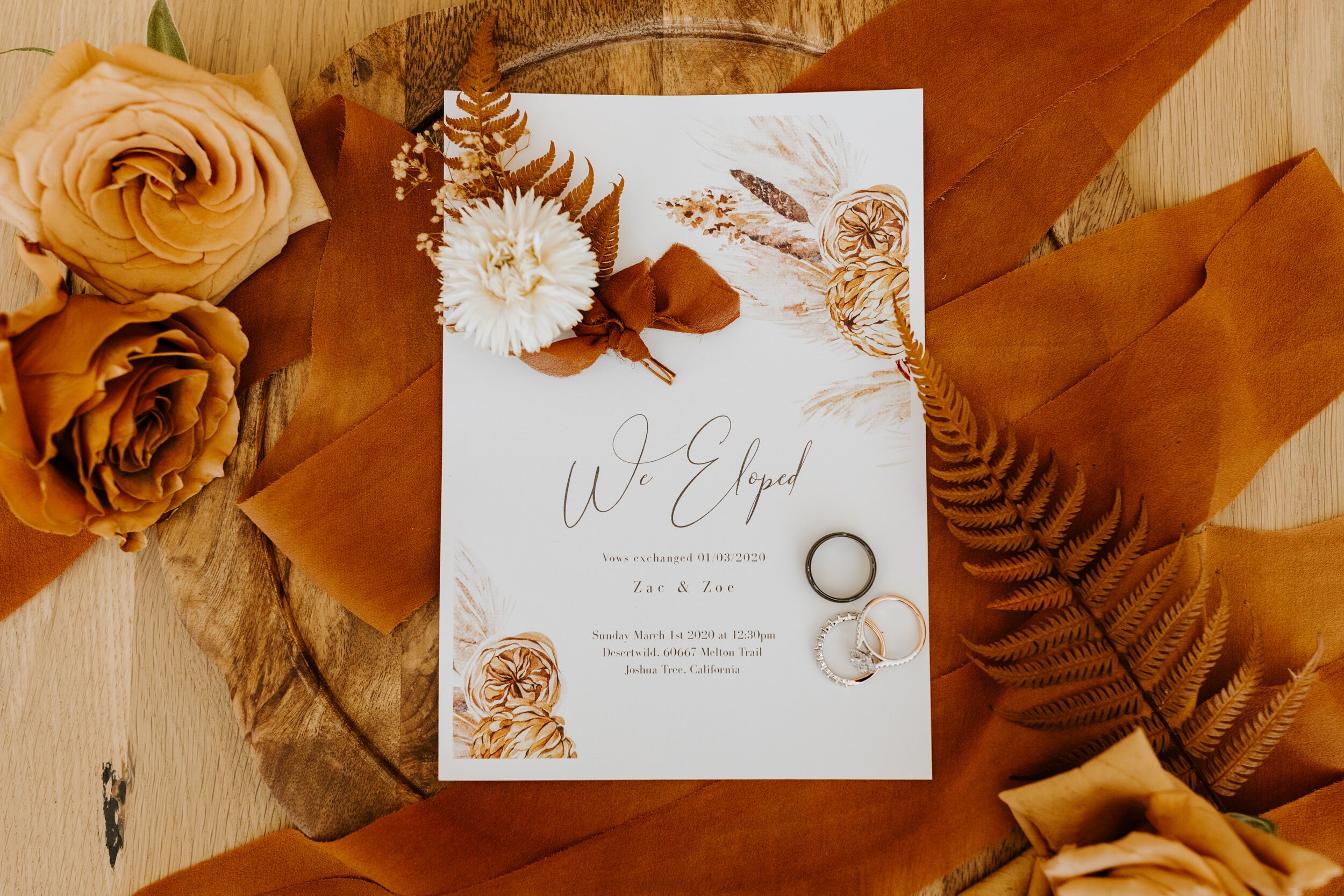 Neutral rust we eloped sign with flowers ribbon and rings flat-lay | Joshua Tree Elopement | Tida Svy | www.tidasvy.com