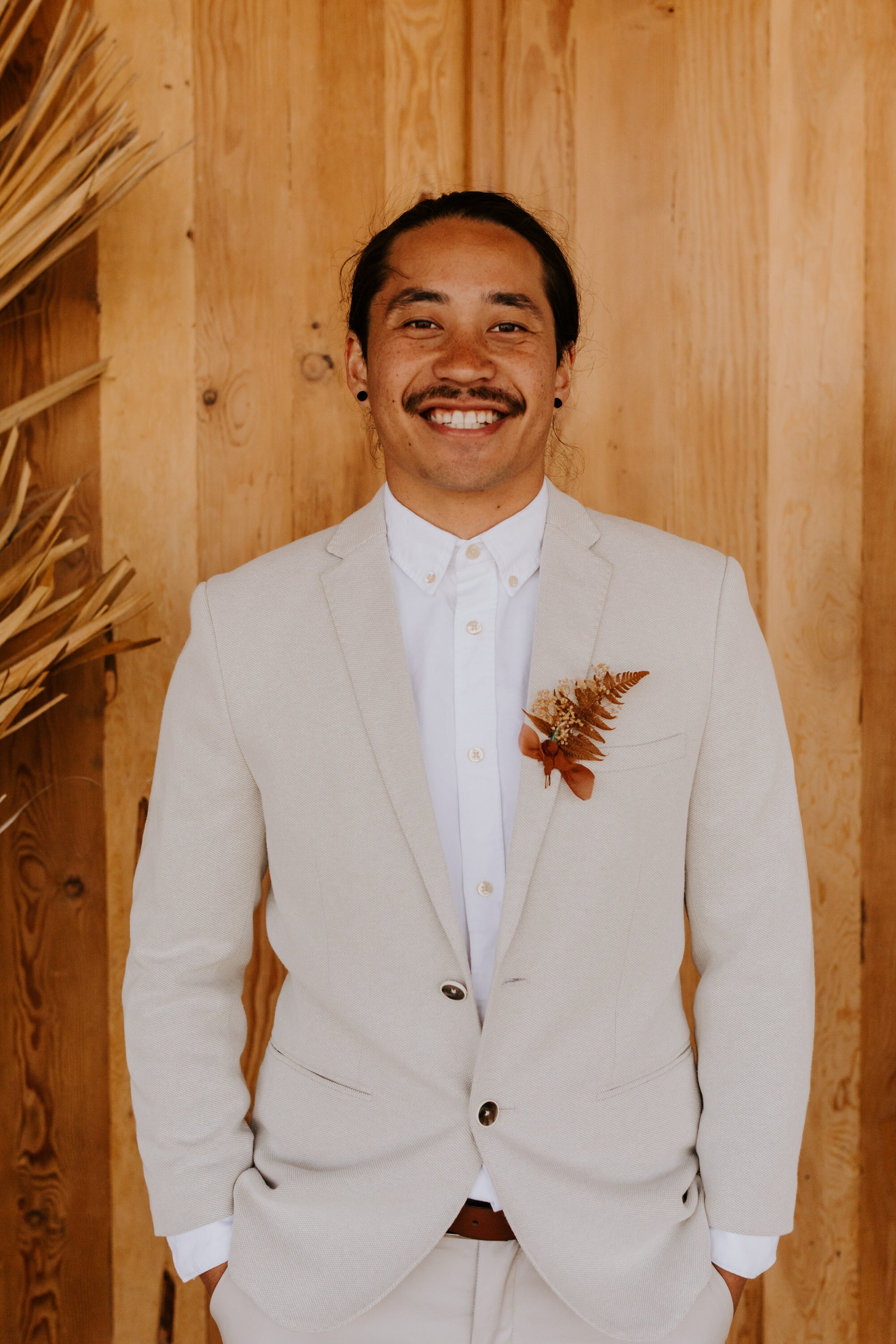 Groom with cream suit and rust boutonniere | Boho Joshua Tree elopement at Desert Wild JT airbnb | Dried palm leaves, pampas grass, neutral rust florals | Tida Svy | www.tidasvy.com