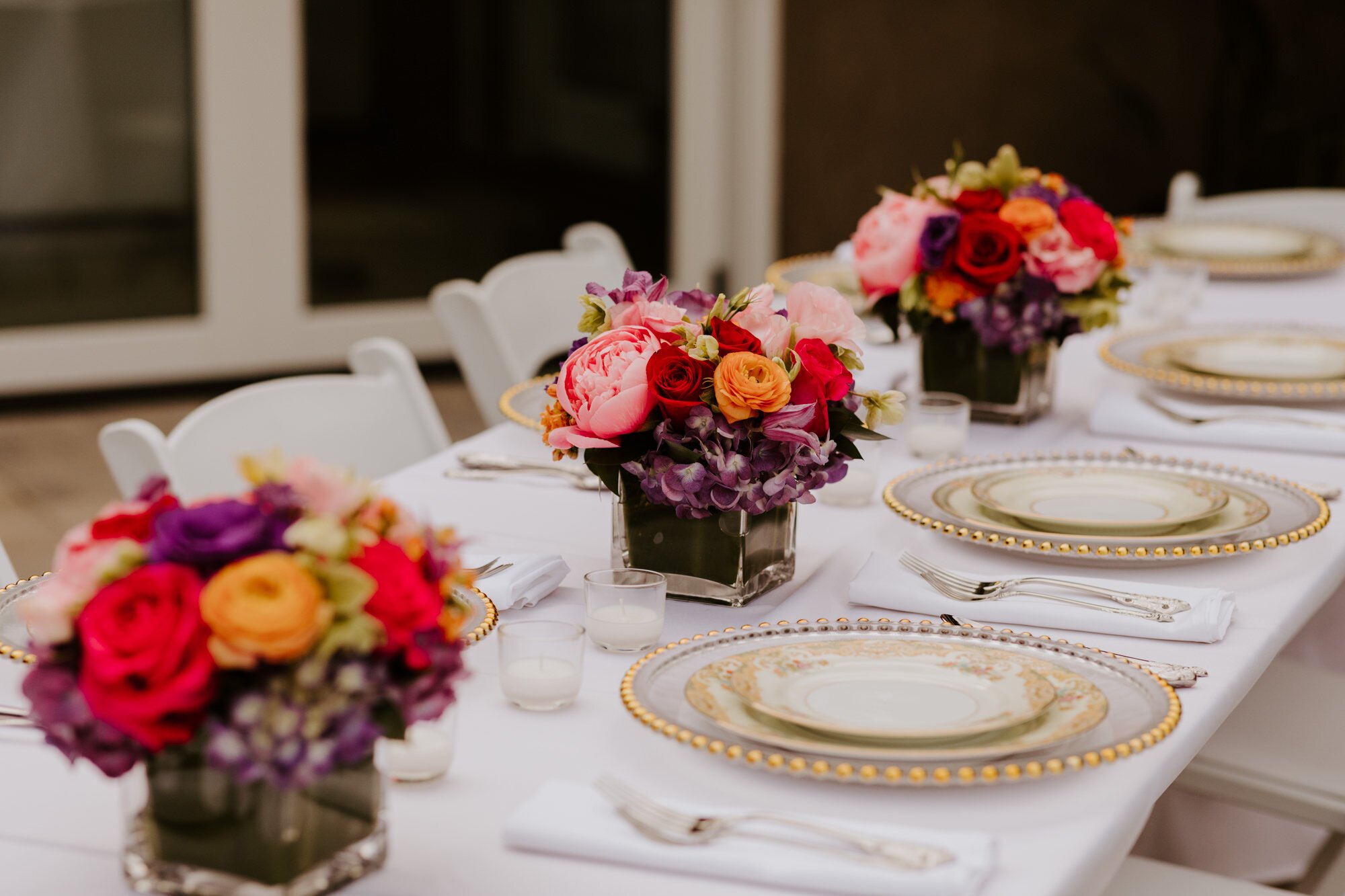 Minimalist and simple wedding table setting, colorful pink purple and orange flower centerpieces, gold rimmed white plates, white tablecloth, Tida Svy Photography | www.tidasvy.com