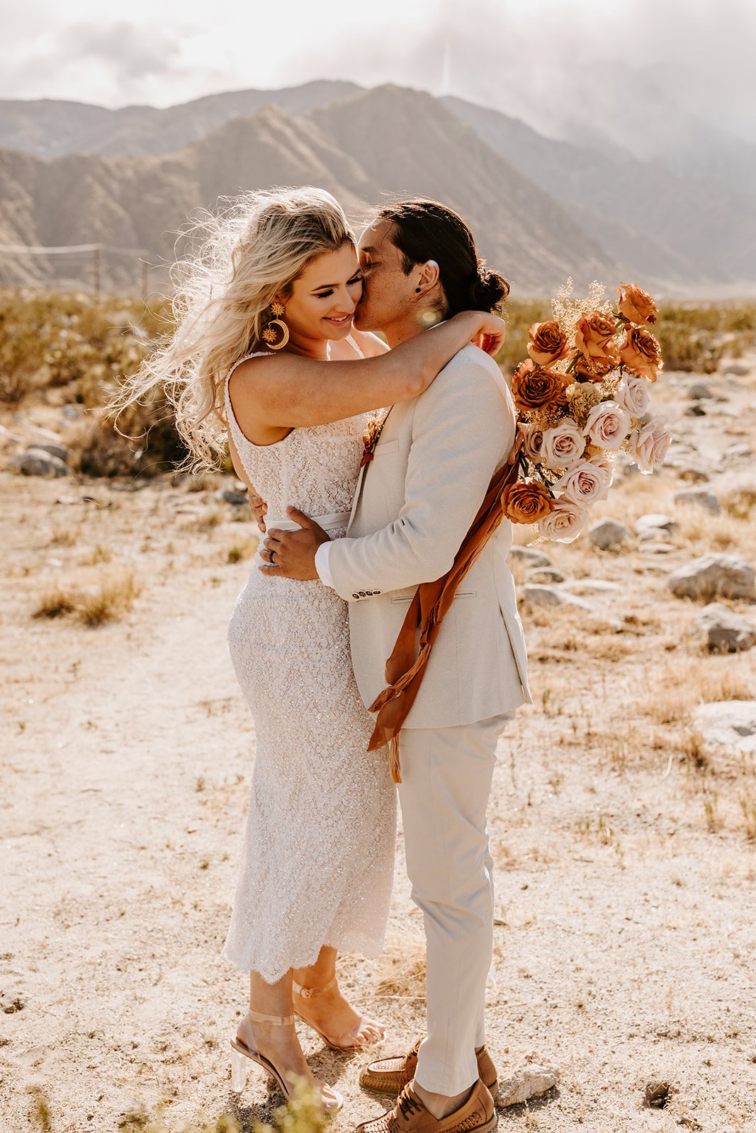 Couple kissing in front of the San Jacinto Mountains in the Palm Springs desert during wedding portraits by Tida Svy