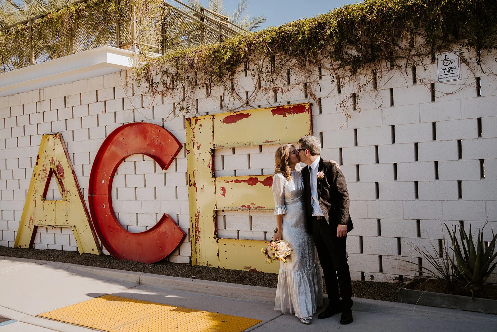 Couple kissing in front of the Ace Hotel sign Palm Springs wedding photographed by Tida Svy