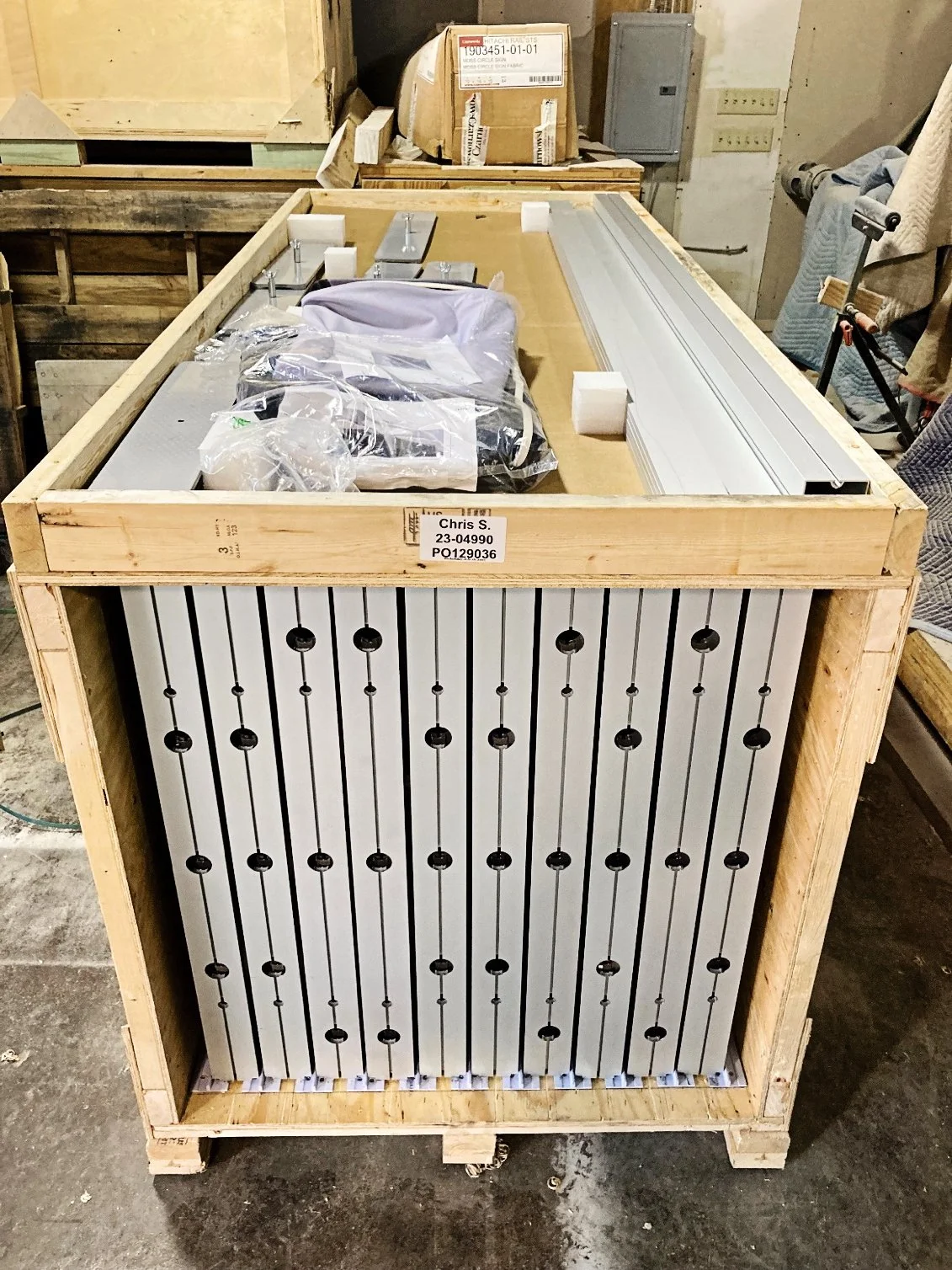 Finished metal panels separated by foam inside a labelled wooden shipping crate
