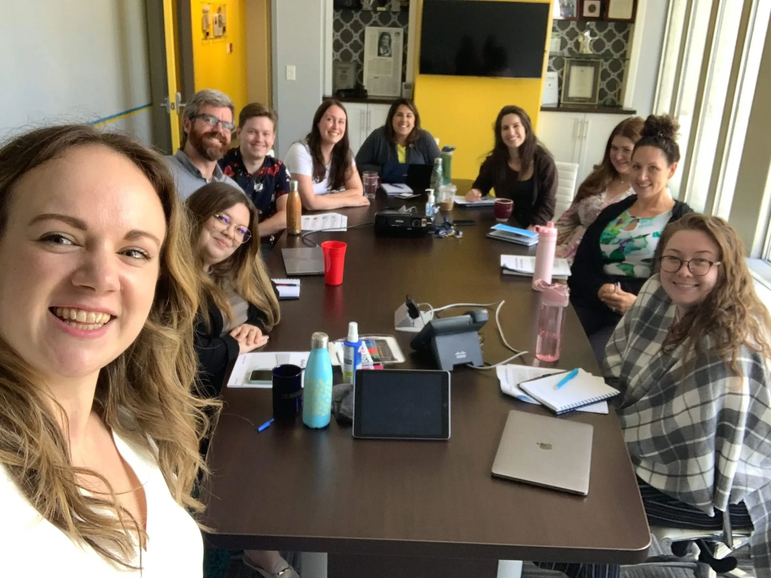 A group of participants smiling around a table during a workshop.