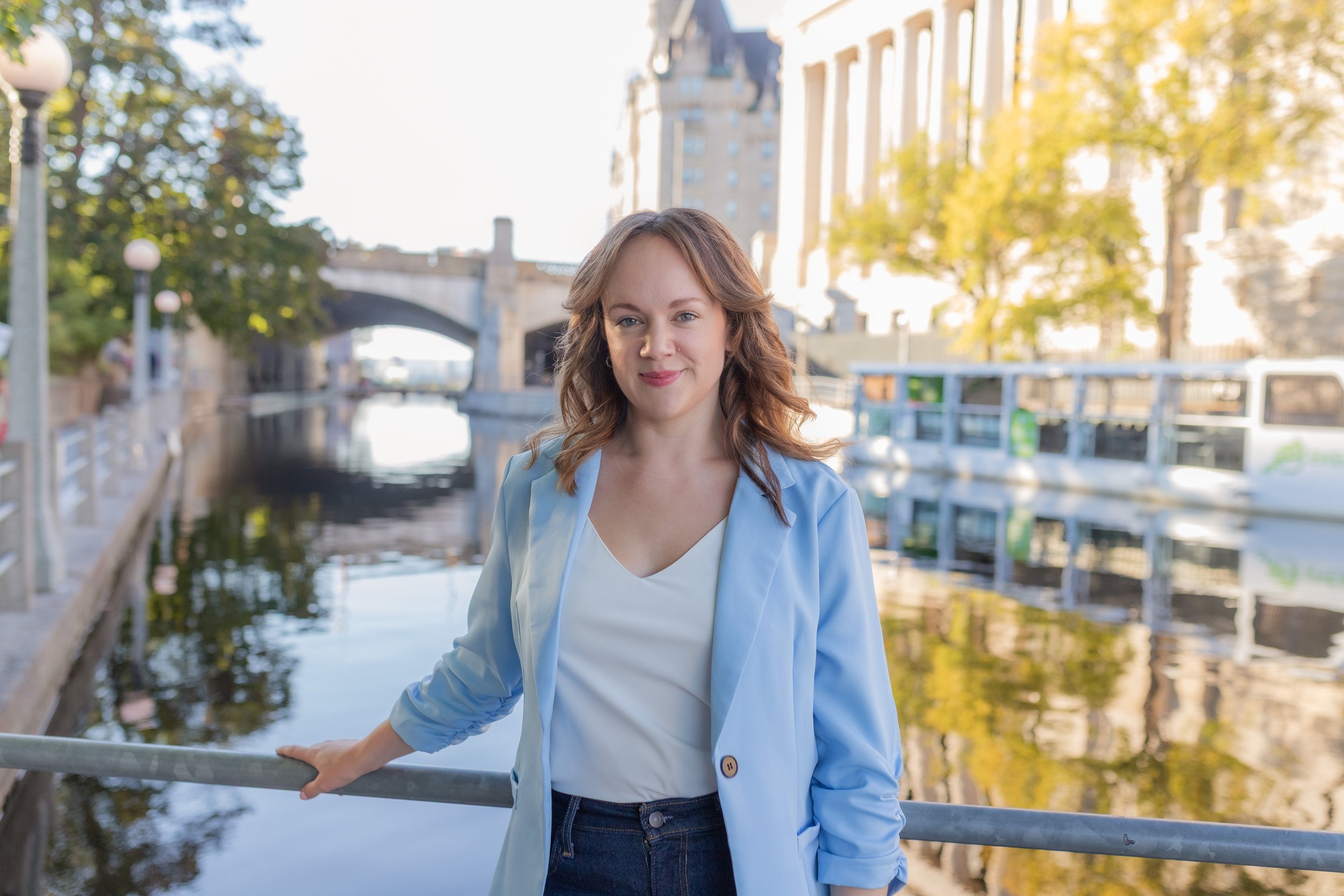 Women in a blue blazer standing by a canal