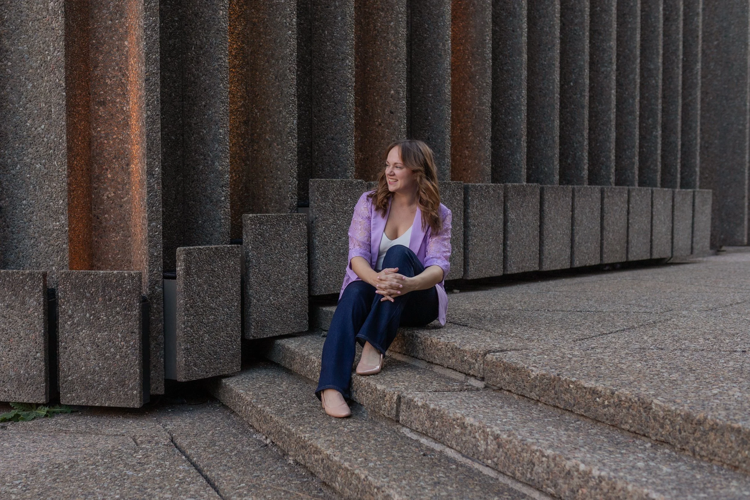 Nina Nesdoly sitting and smiling on stone steps.