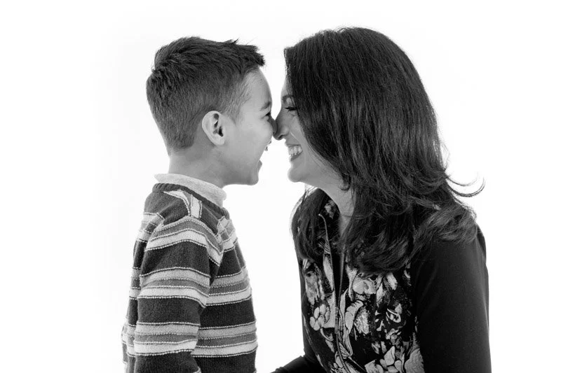 Studio portrait of a young boy and mum are touching noses, smiling, with their foreheads and noses close together, photographed by Natural Family Photography in Melbourne.