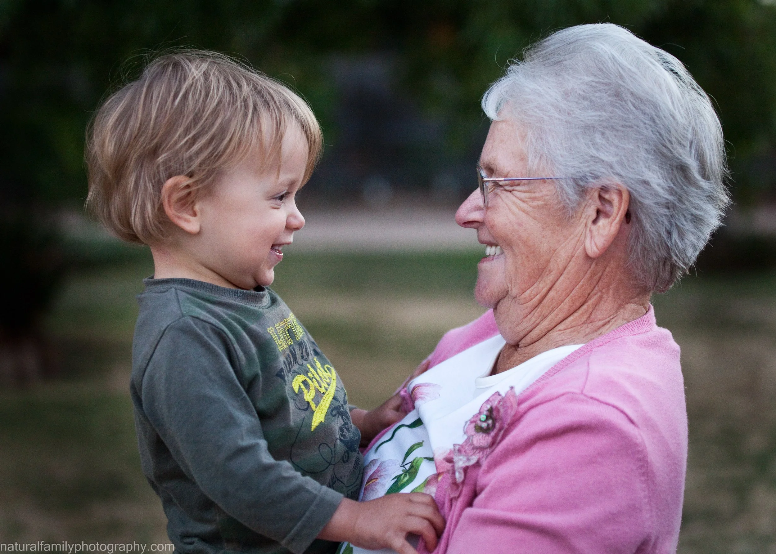Great-grandmother and great-grandson smiling at each other outdoors. Generational portraits by Natural Family Photography, Melbourne.