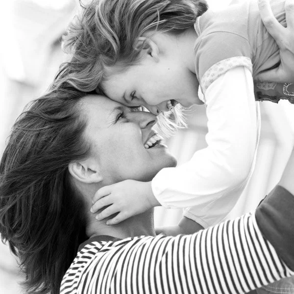 A mother and daughter smiling and touching foreheads, sharing a joyful moment. Black and white portrait captured by Natural Family Photography, Melbourne.