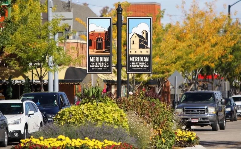 Street scene in Meridian Downtown with historic signs, cars, and fall foliage.