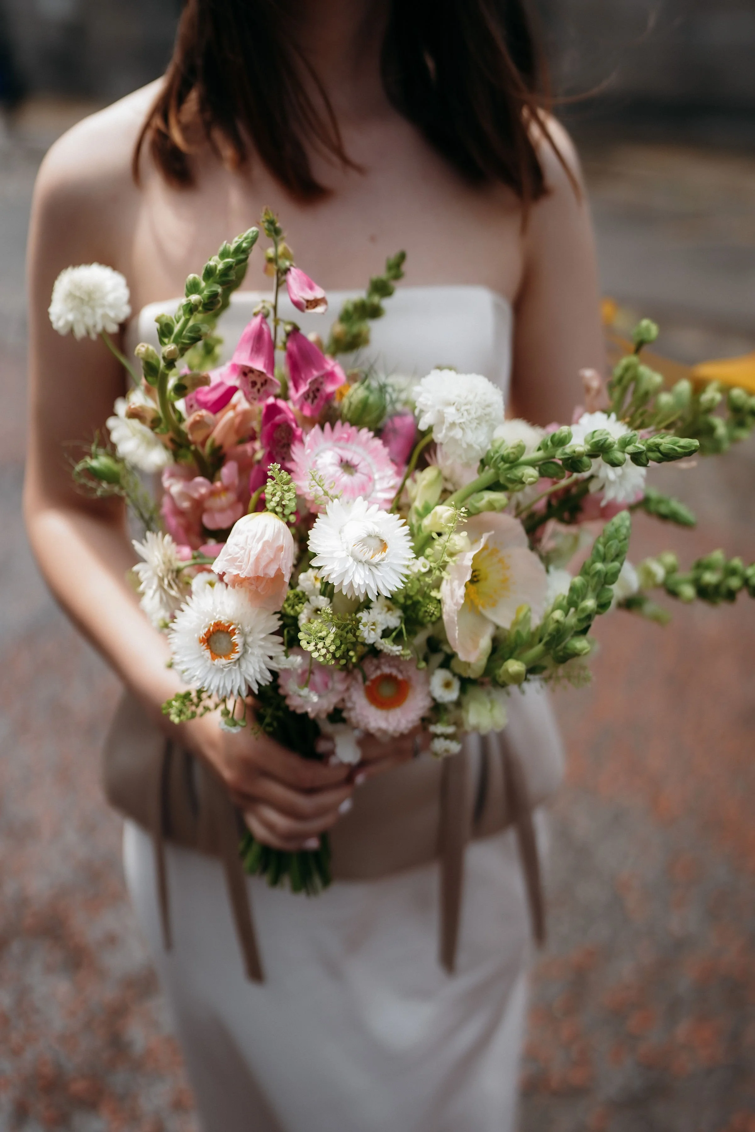 Woman in a white dress holding a colorful bouquet of flowers.