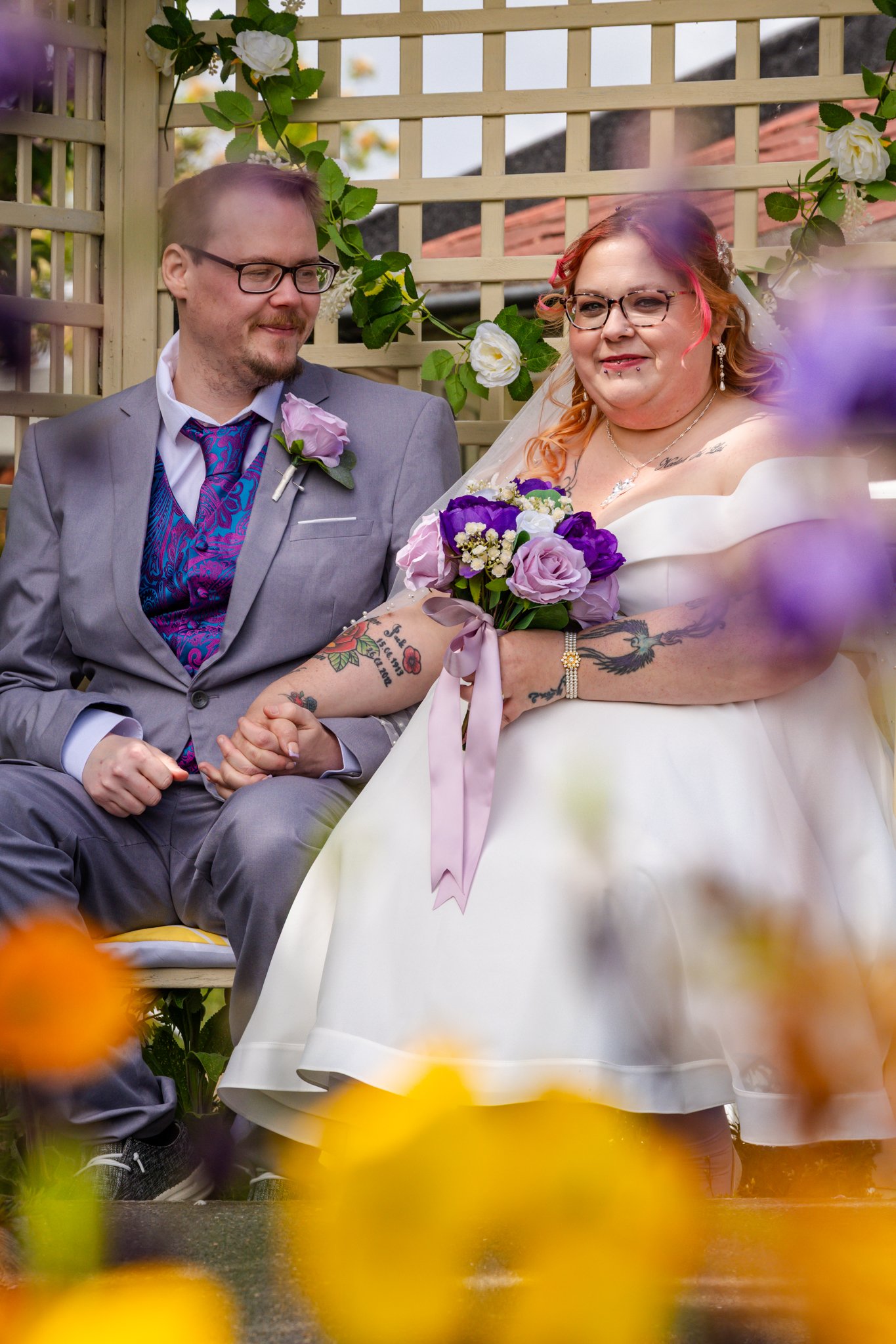 Bride and Groom are posed in the garden and framed with flowers in the foreground