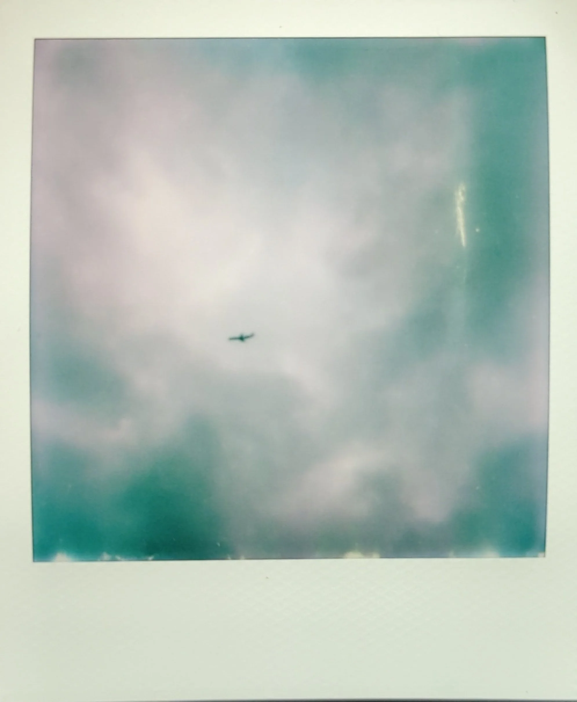 a polaroid photo of an airplane flying through a cloudy sky