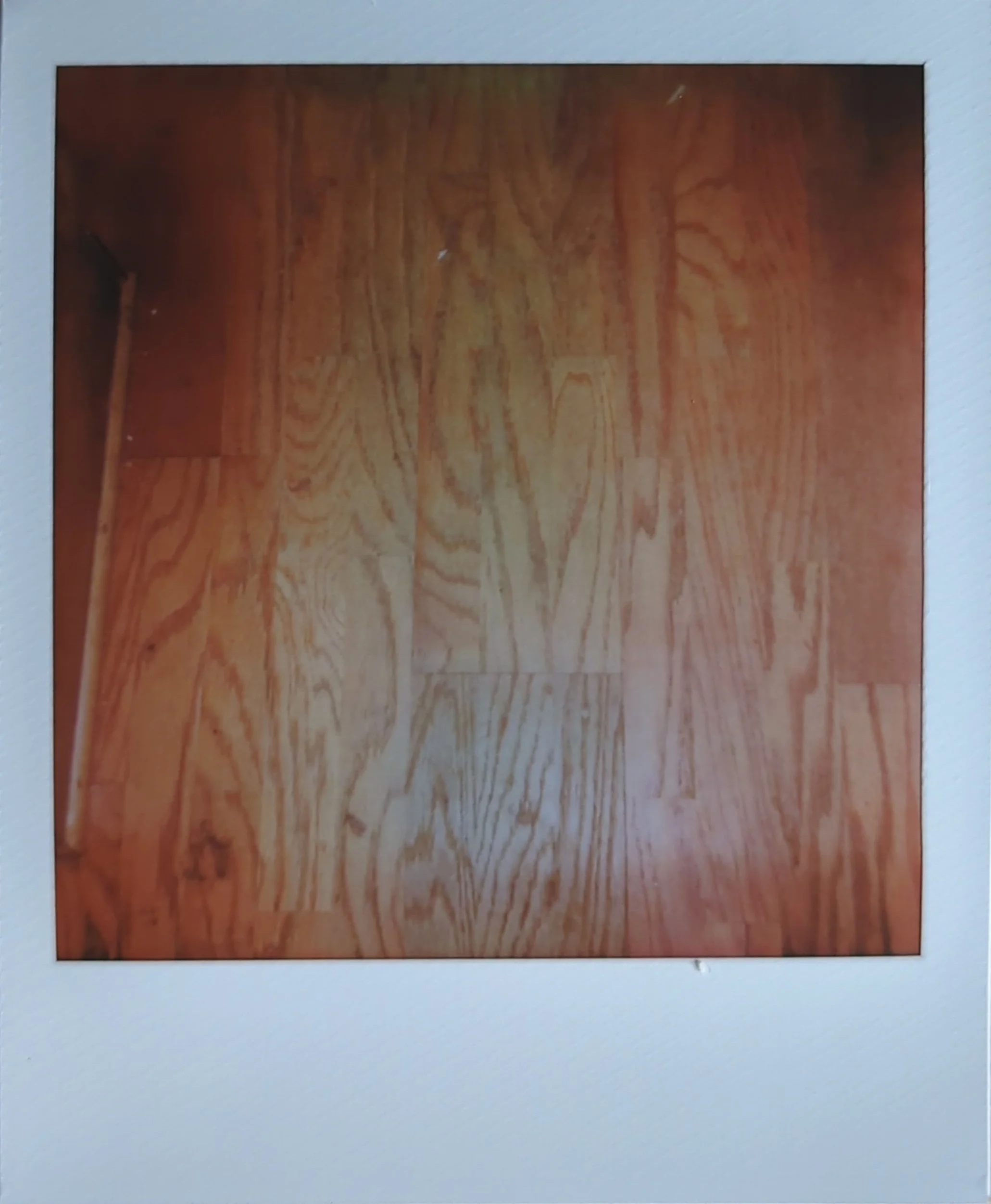 polaroid photo of a hardwood floor with a heart in it