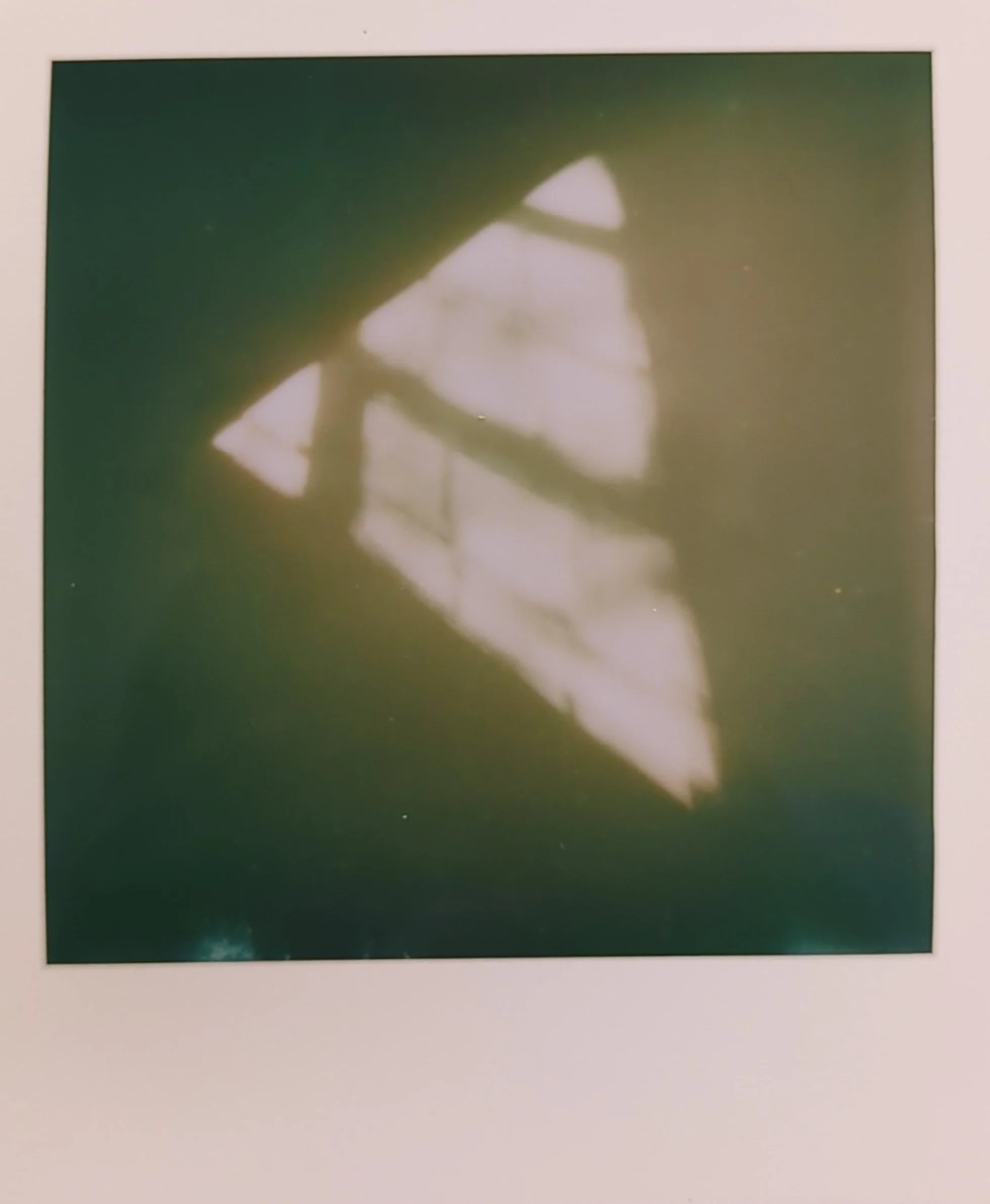 a polaroid photo of light from a window that is shaped like a triangle